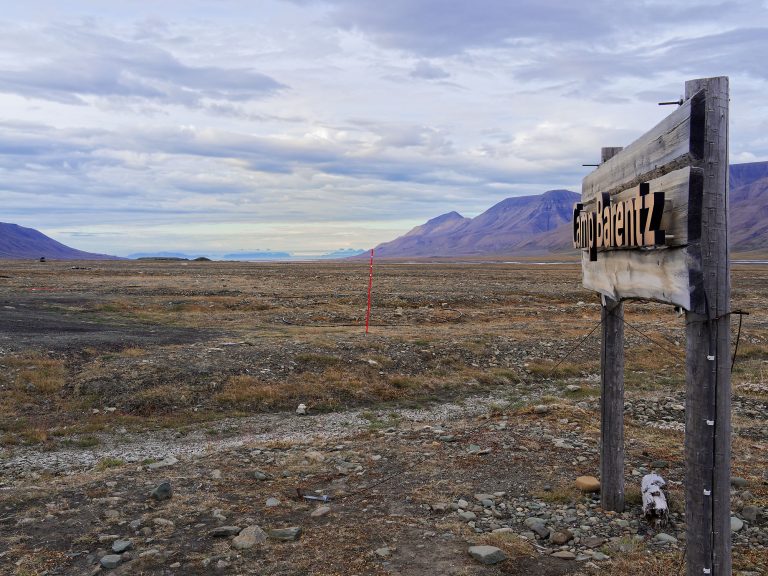 Svalbard: Camp Barentz Schild vor arktischer Landschaft. Berge im Hintergrund.