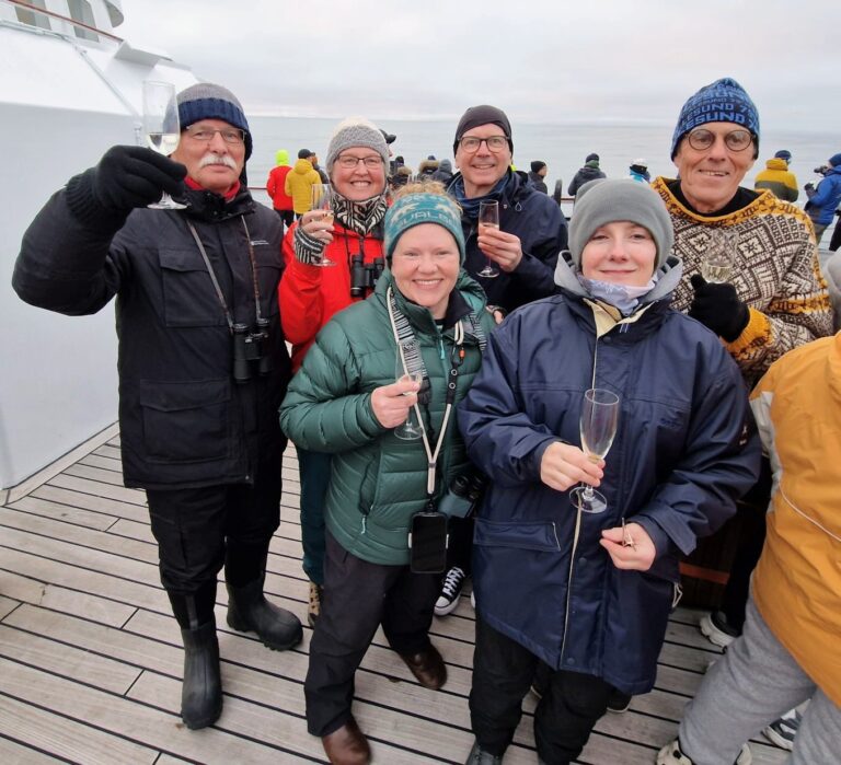 Reisegruppe am 80. Breitengrad, Spitzbergen. Feiern mit Sekt auf dem Schiff. Arktis-Kreuzfahrt.