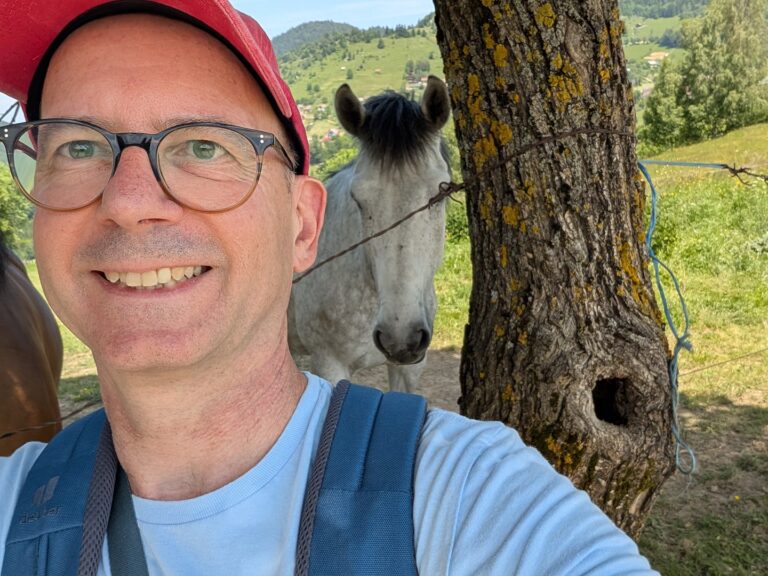 Landschaft im Piatra-Craiului-Gebirge, Rumänien. Mann mit Rucksack, Pferd im Hintergrund. Natur, Wandern, Karpaten.