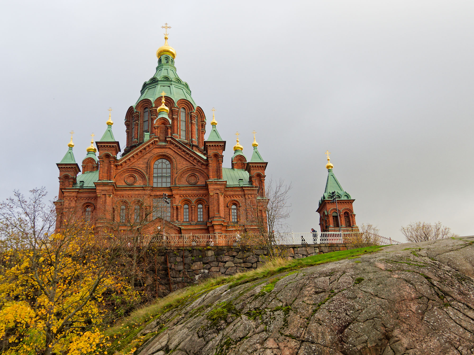 Uspenski Kathedrale in Helsinki, Finnland. Rote Backsteinkirche mit grünen und goldenen Kuppeln auf einem Felsen.