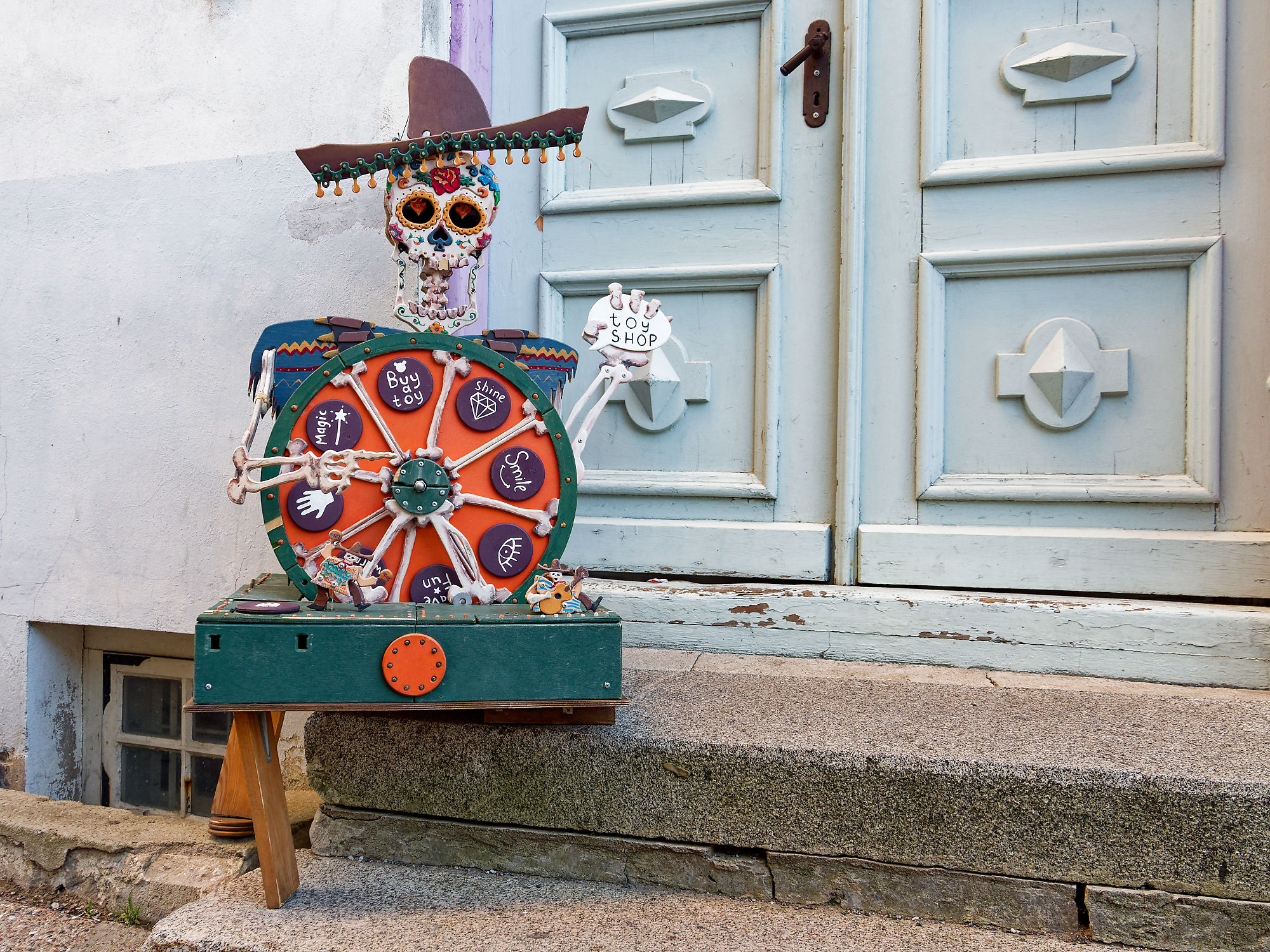 Tallinn Spielzeugladen: Skelett mit Sombrero und Glücksrad vor blauer Tür. Kunsthandwerk in Estland.