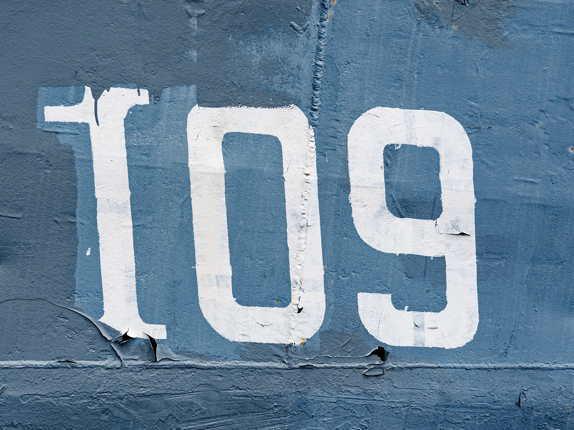 Weiße Nummer 109 auf blauem Metall. Abgenutzte Farbe, industrielles Design.