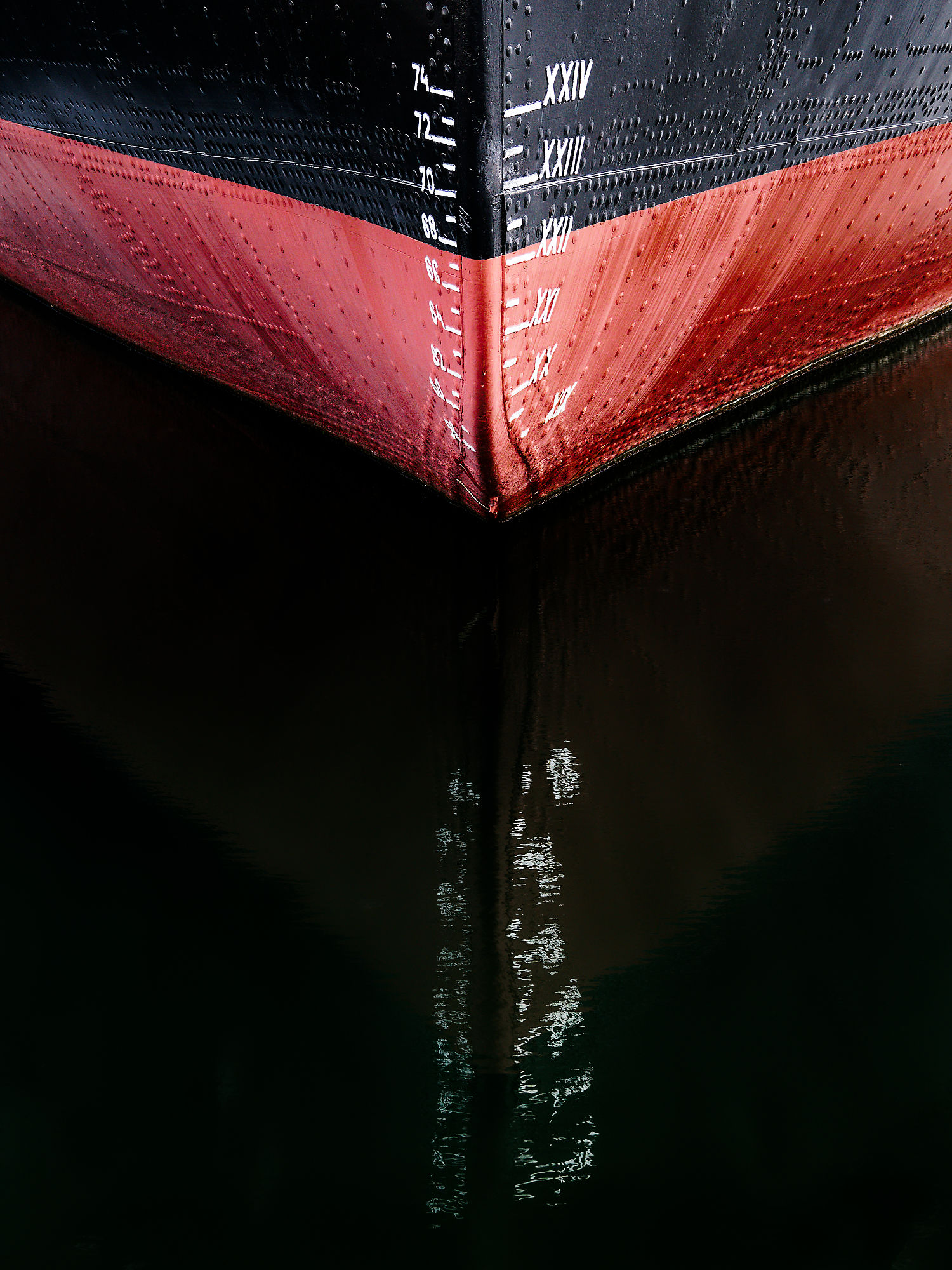 Bugspitze eines Schiffes in Tallinn, Estland. Rot und Schwarz mit Tiefgangsanzeige. Spiegelung im Wasser.