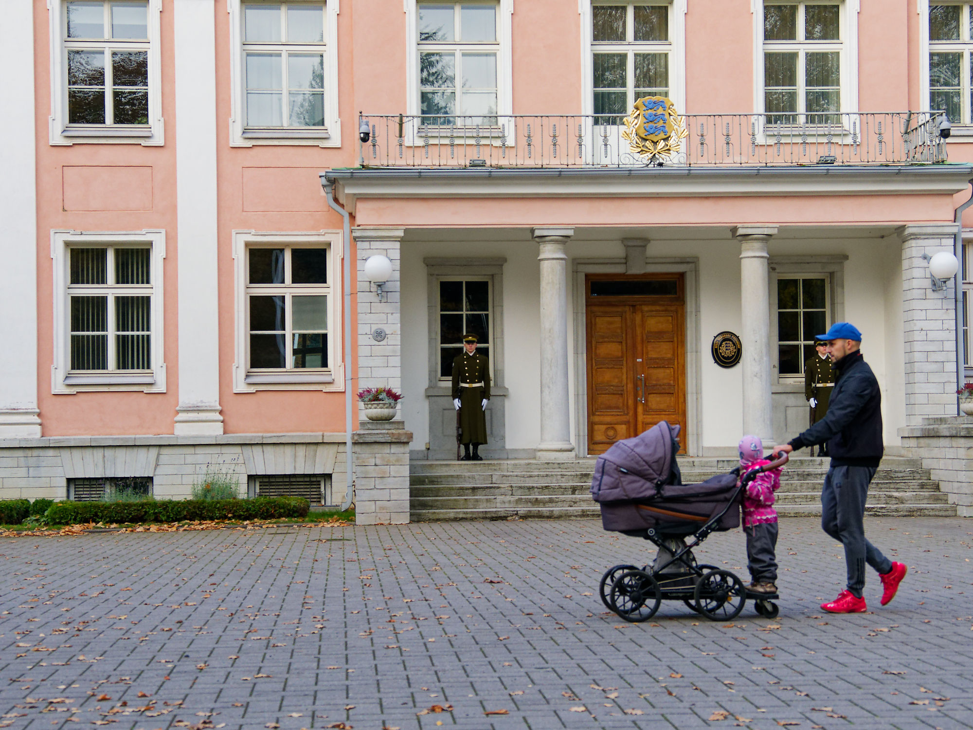 Tallinn, Estland: Vater schiebt Kinderwagen vor dem Präsidentenpalast. Wachmann steht Wache. Architektur und Familie in Tallinn.