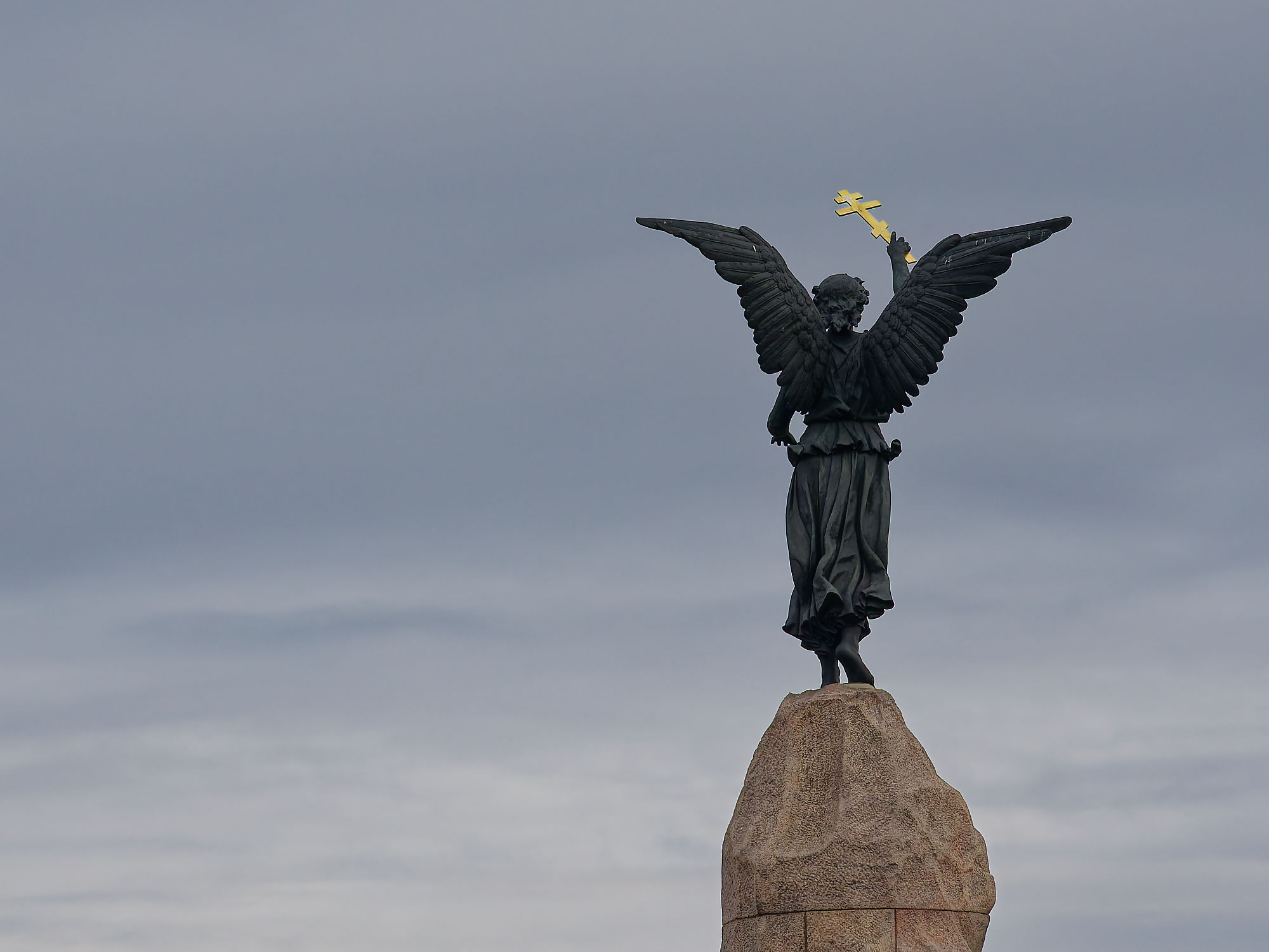 Russalka-Denkmal in Tallinn, Estland. Statue mit goldenem Kreuz auf einem Felsen gegen bewölkten Himmel. Sehenswürdigkeit.