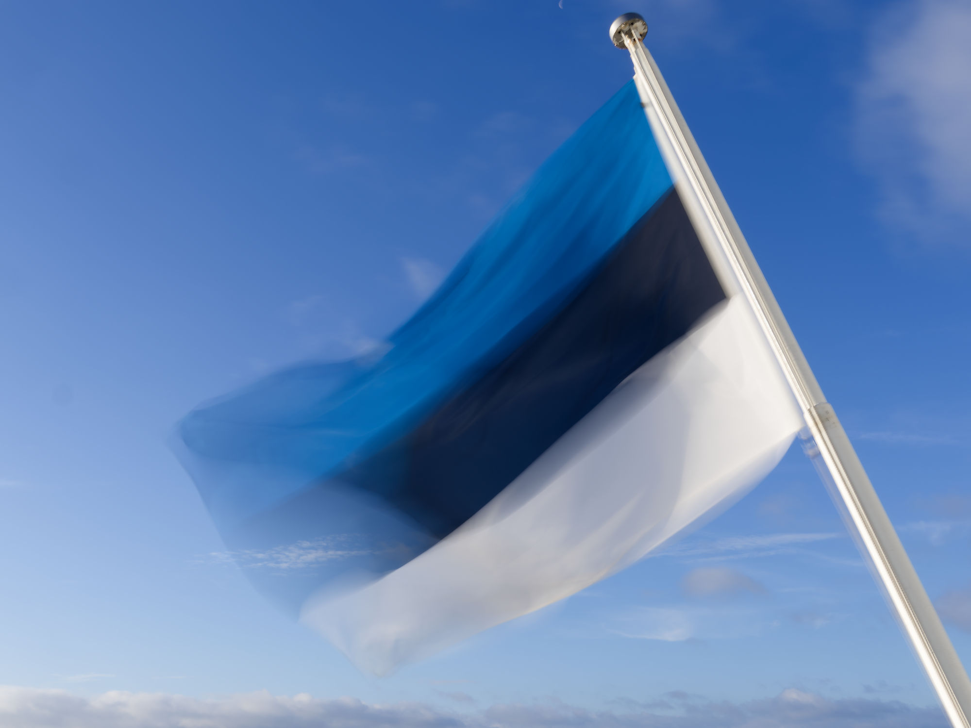 Estnische Flagge weht im Wind vor blauem Himmel. Tallinn, Estland.