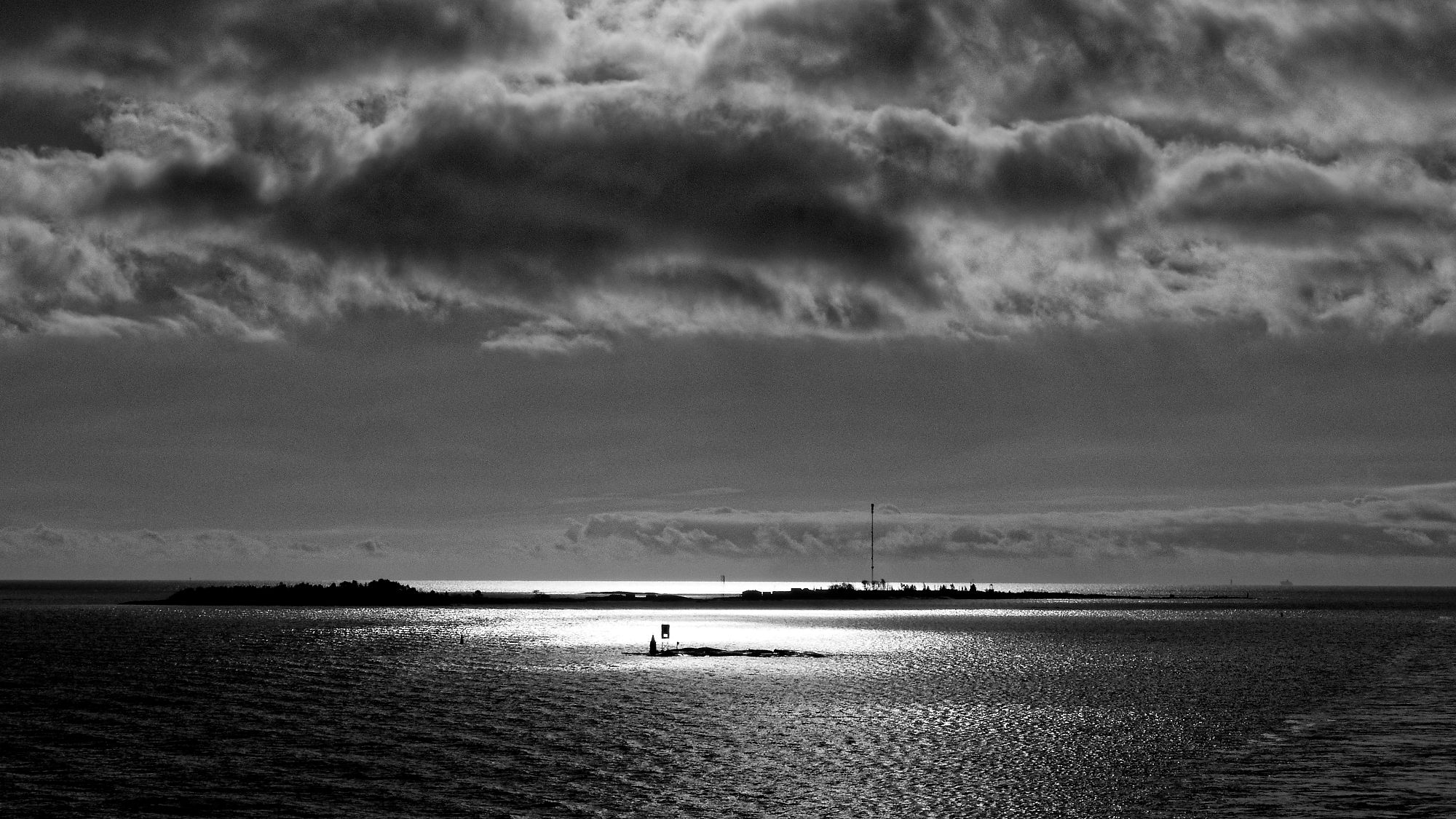 Schwarzweiß-Foto: Tallinn-Helsinki-Fähre, Inseln im Meer, bewölkter Himmel.