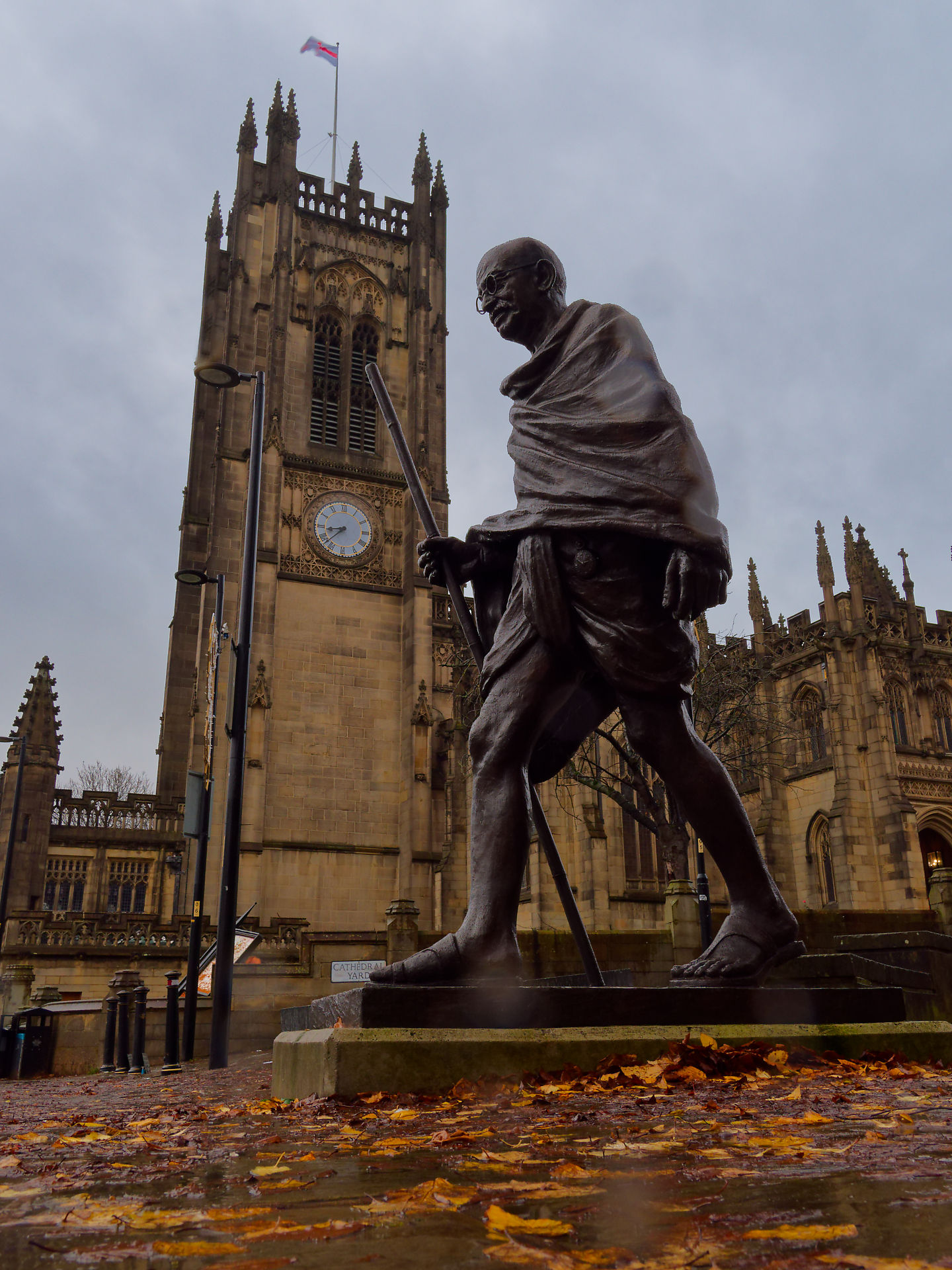 Manchester Statue von Mahatma Gandhi in Manchester vor der Kathedrale. Herbstlaub auf dem Boden.