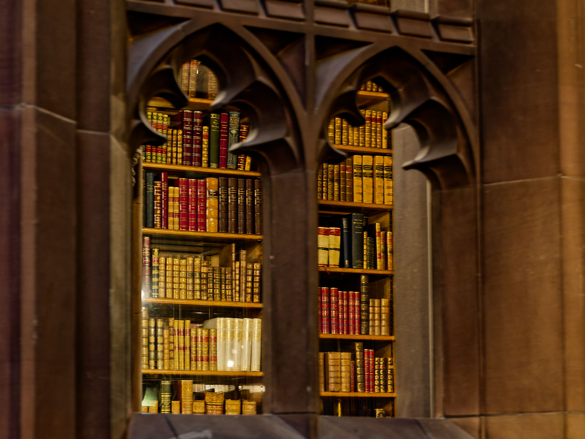 Manchester Bücherregal durch gotisches Fenster in Manchester. Historische Bibliothek mit alten Büchern. Manchester 2025.