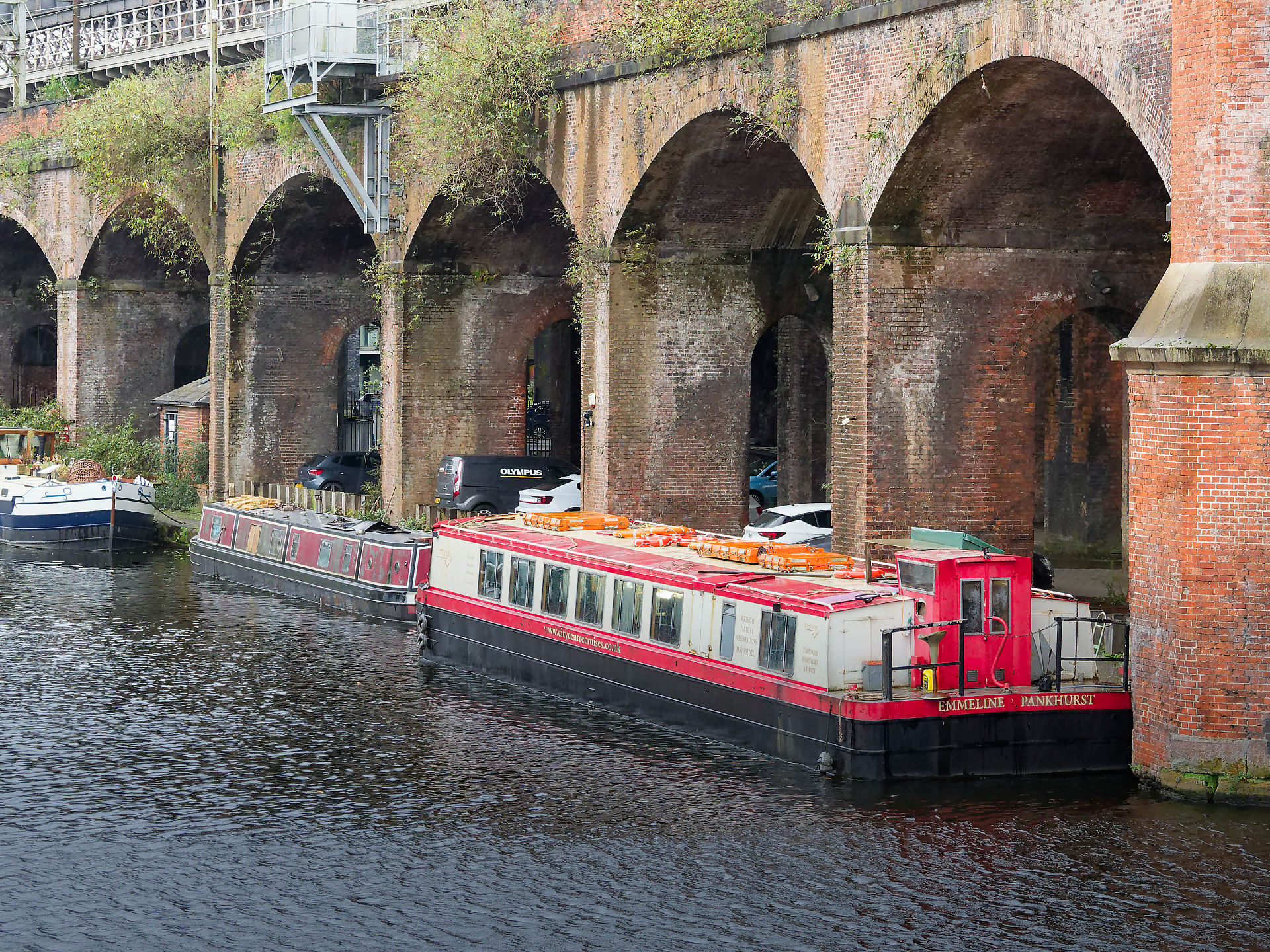 Manchester Manchester Canal scene with narrowboats, brick arches, and reflections in the water. Emmeline Pankhurst boat visible.