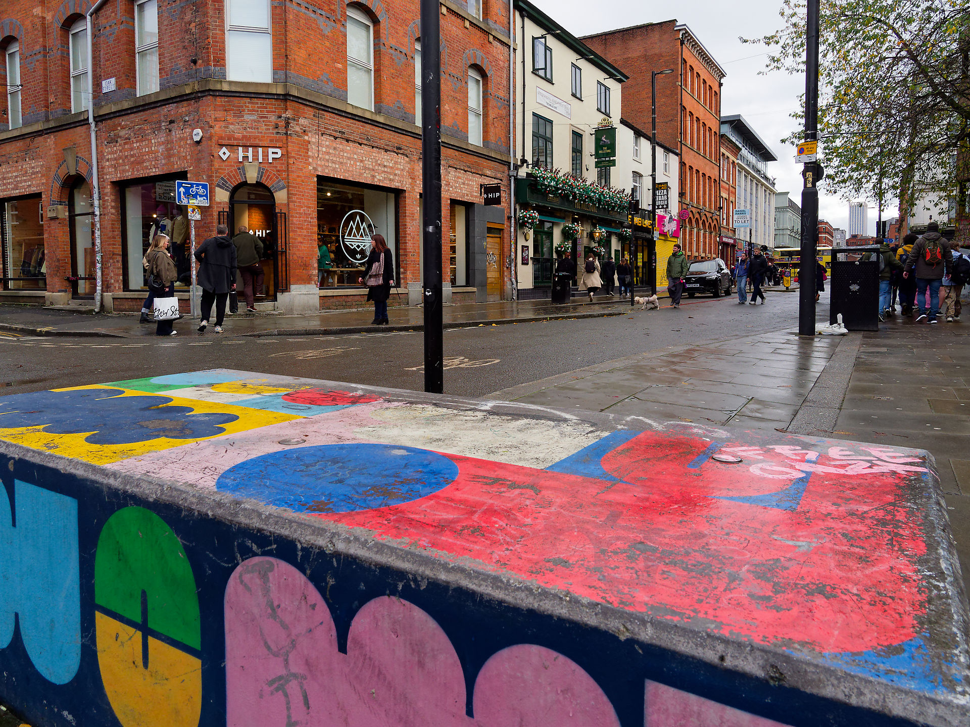 Manchester Buntes Graffiti auf Beton in Manchester, England. Architektur der Stadt und Passanten im Hintergrund. Manchester-20251115-063.jpg