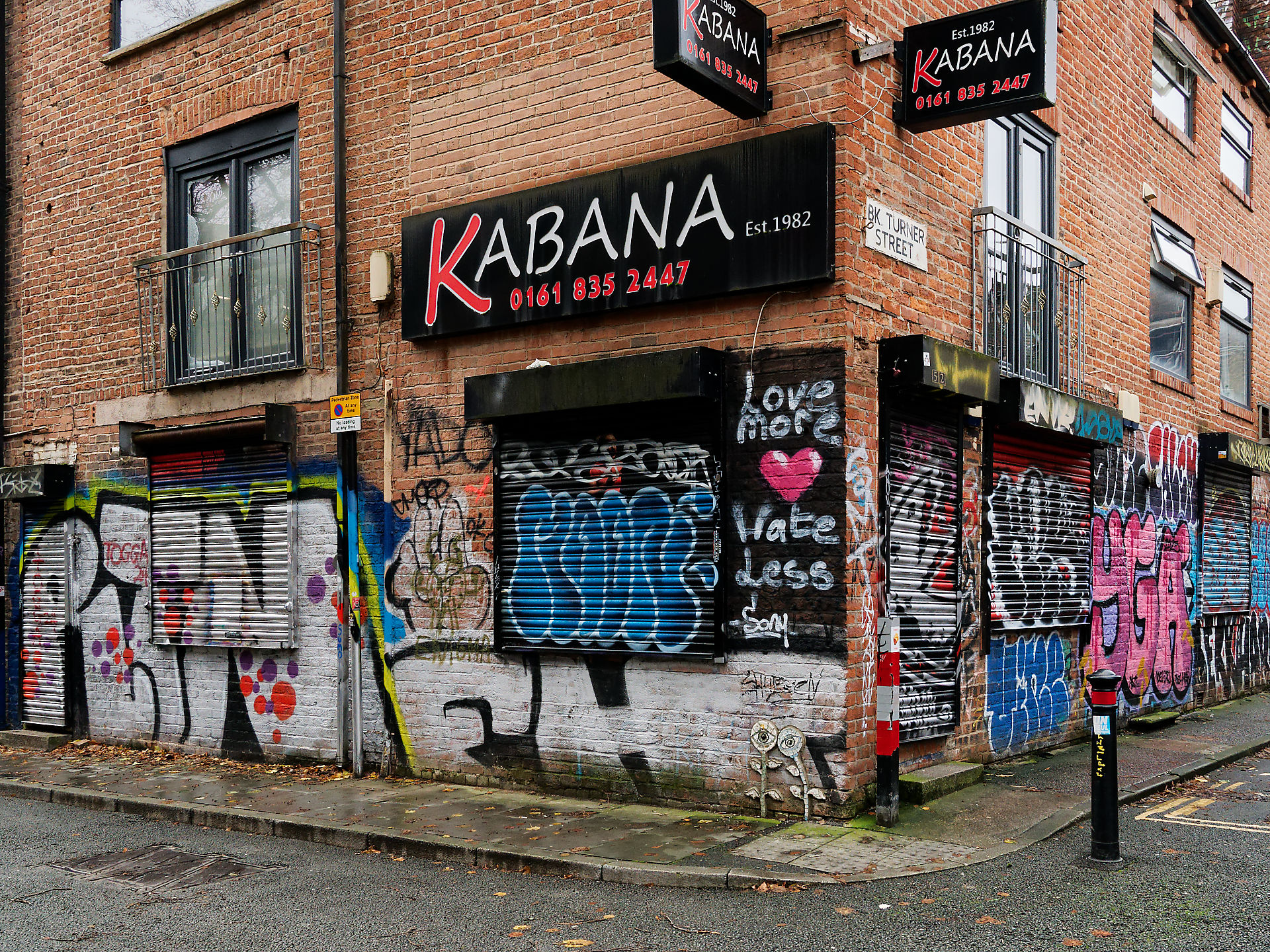 Manchester Manchester street scene with 'Kabana' signs on a brick building covered in graffiti, showcasing urban decay and street art.
