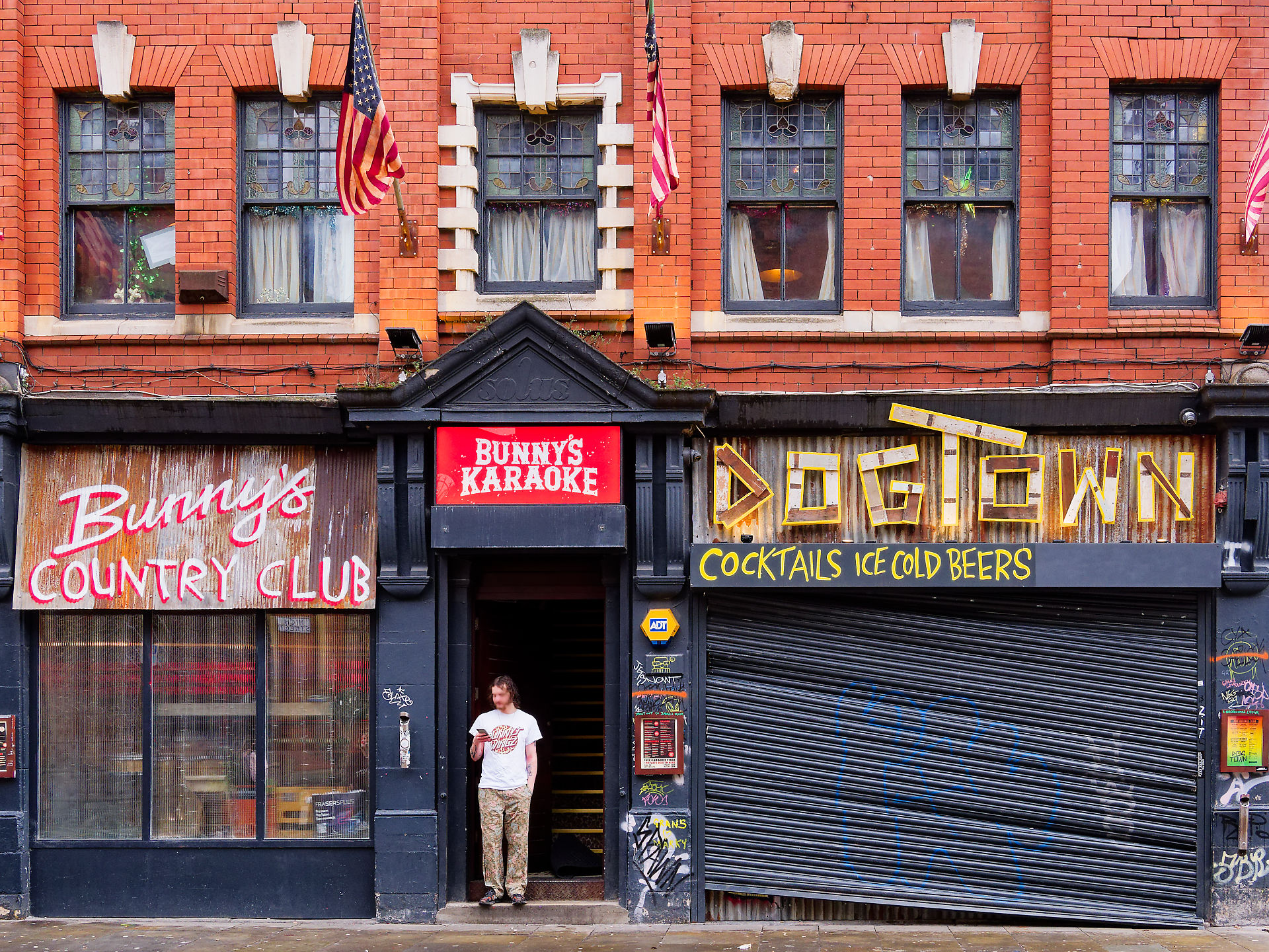 Manchester Bunny's Country Club und Dogtown Bar Fassade in Manchester. Mann steht im Eingang von Bunny's Karaoke.