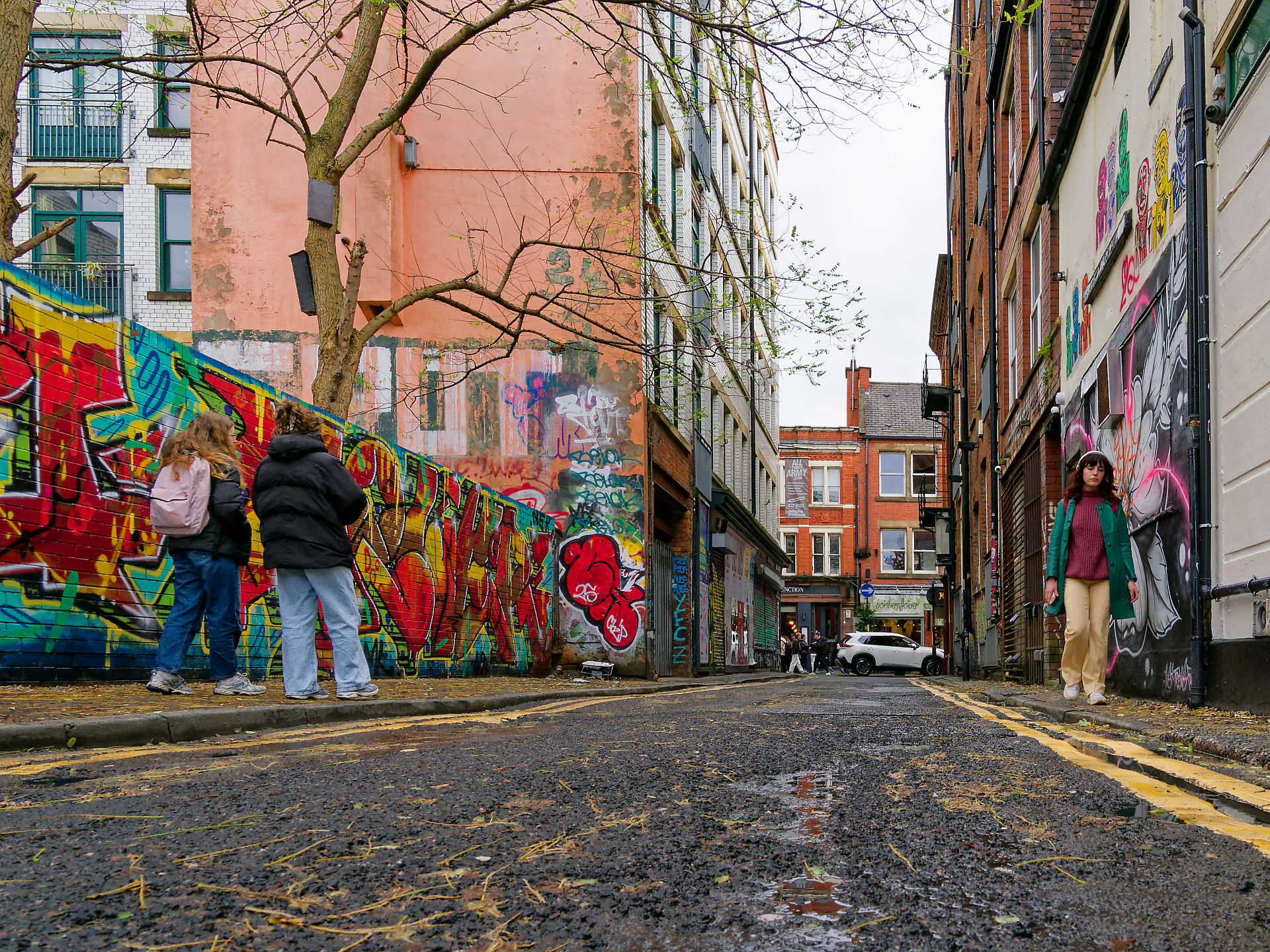 Manchester Bunte Graffiti in Manchester, England. Menschen bewundern Streetart in einer Gasse. Städtische Kunstszene.