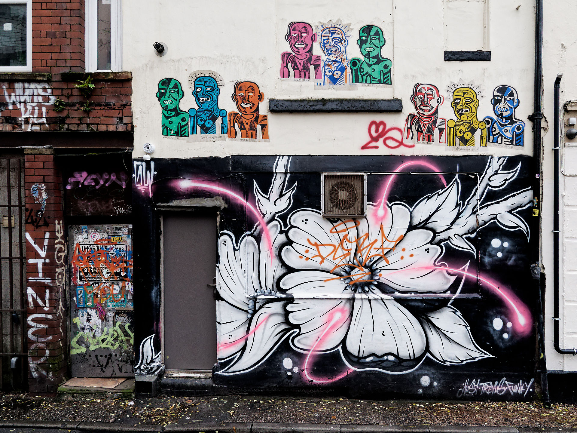 Manchester Manchester Street Art: Fassade mit Graffiti-Blume und bunten Figuren an einer Hauswand in Manchester.