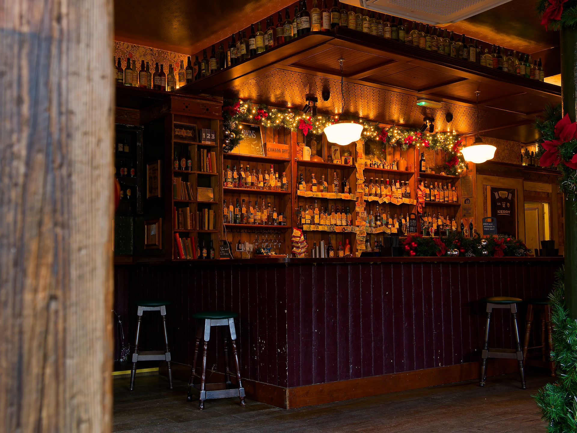 Manchester Gemütliche Bar in Manchester mit festlicher Dekoration, vollen Regalen und Hockern.