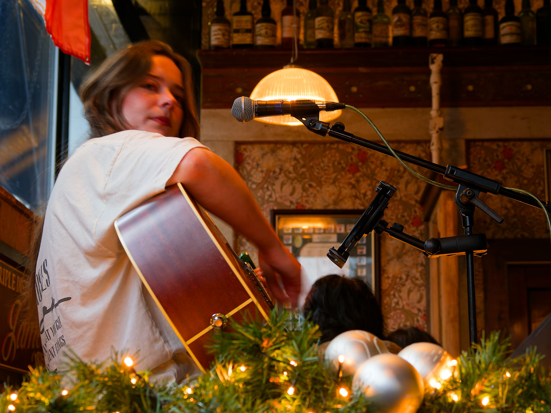 Manchester Frau spielt Gitarre in Manchester Pub. Live-Musik Event. Akustikgitarre und Mikrofon im Pub.
