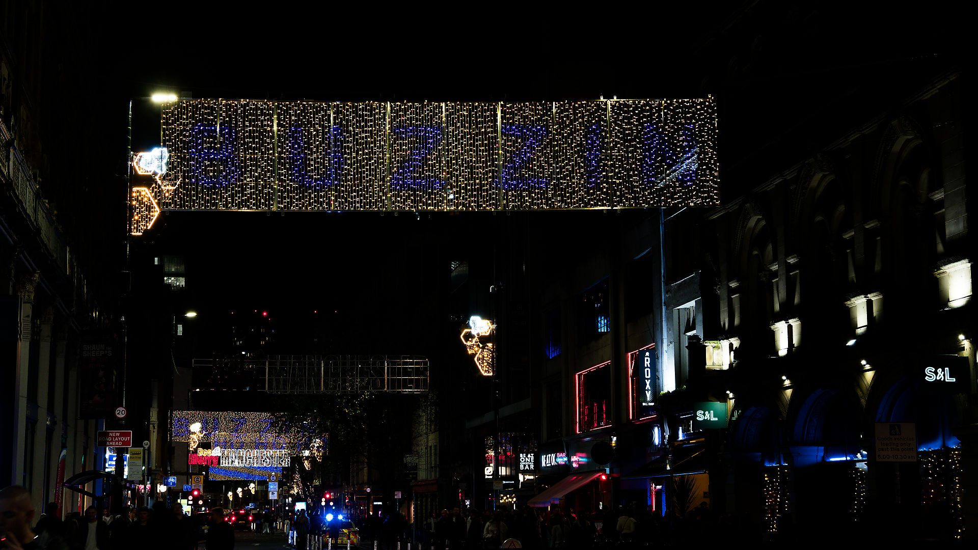 Manchester Manchester Weihnachtsbeleuchtung: Lichterkette mit Sternen und festlicher Dekoration in der Nacht.