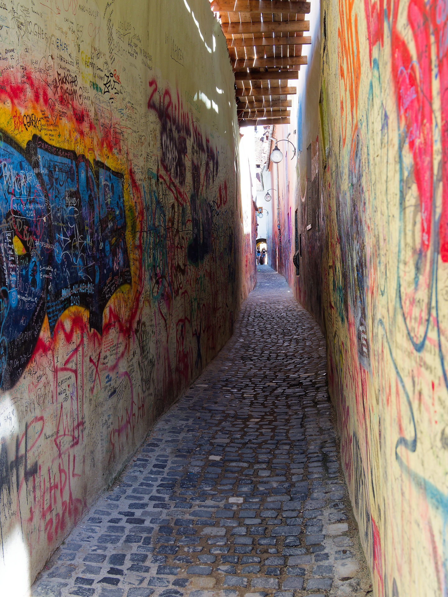 Brasov, Rumänien: Schmale Gasse mit Graffiti und Kopfsteinpflaster. Sehenswürdigkeit in Siebenbürgen.