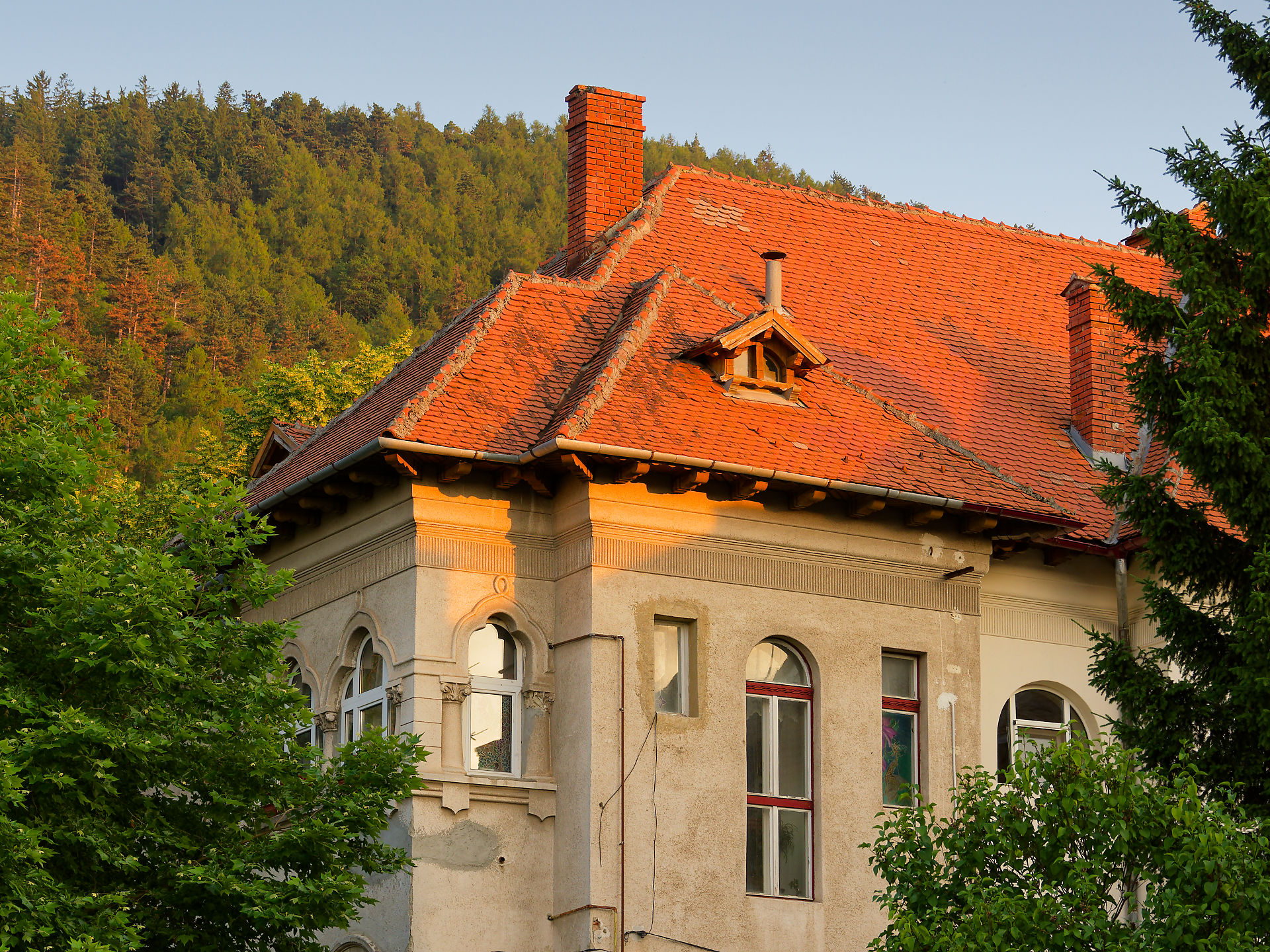 Architektur in Brasov, Rumänien: Haus mit rotem Ziegeldach und Schornstein vor Wald. Urlaub in Siebenbürgen.
