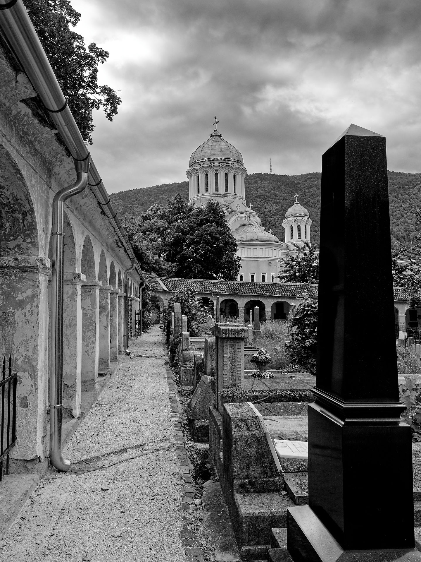 Schwarzes Foto: Friedhof in Brasov, Rumänien, mit Kirche, Grabsteinen und Arkaden. Historische Stätte.
