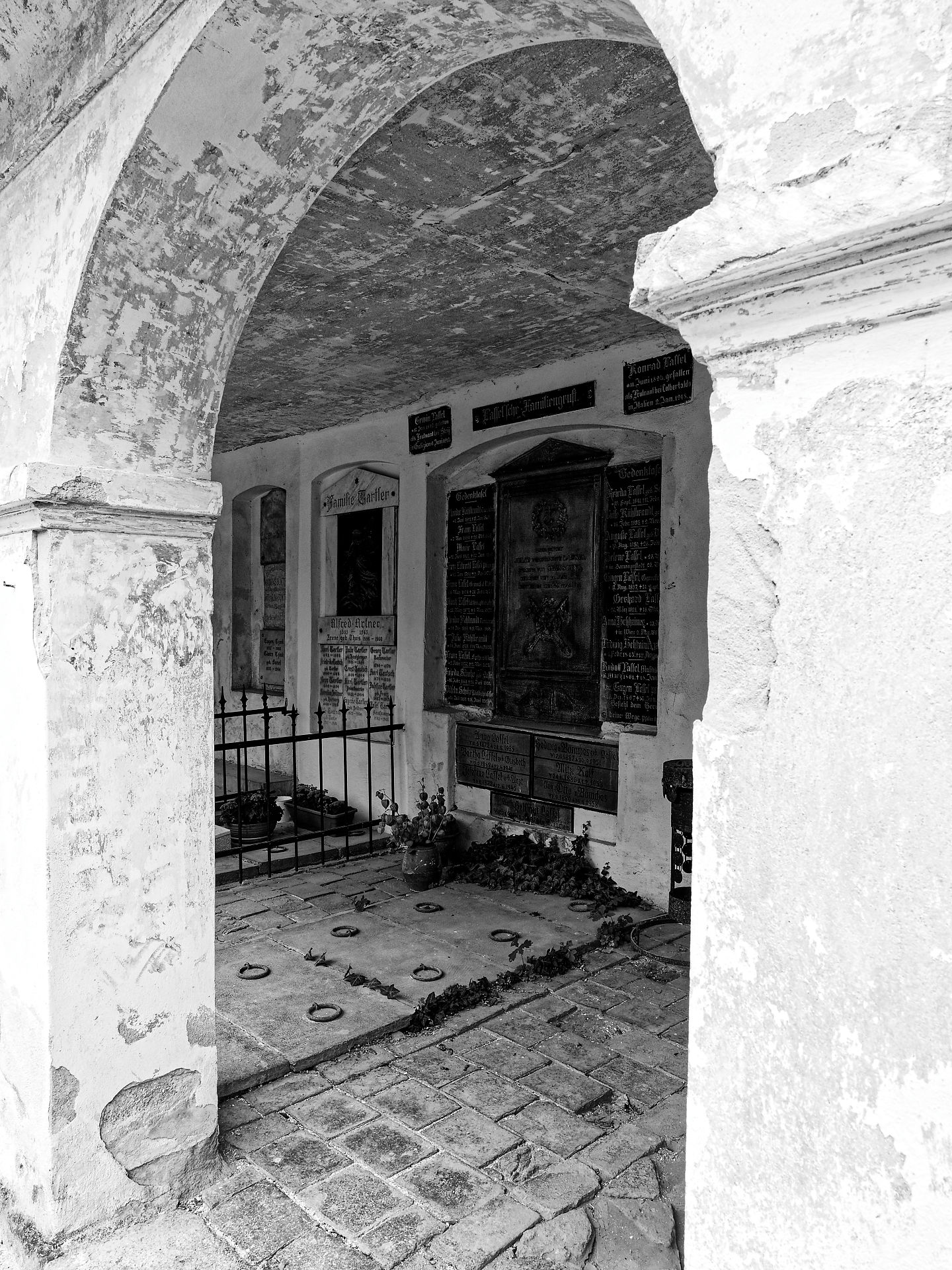 Brasov, Rumänien: Schwarzes und weißes Foto eines alten Friedhofs mit Grabsteinen unter einem Bogen.