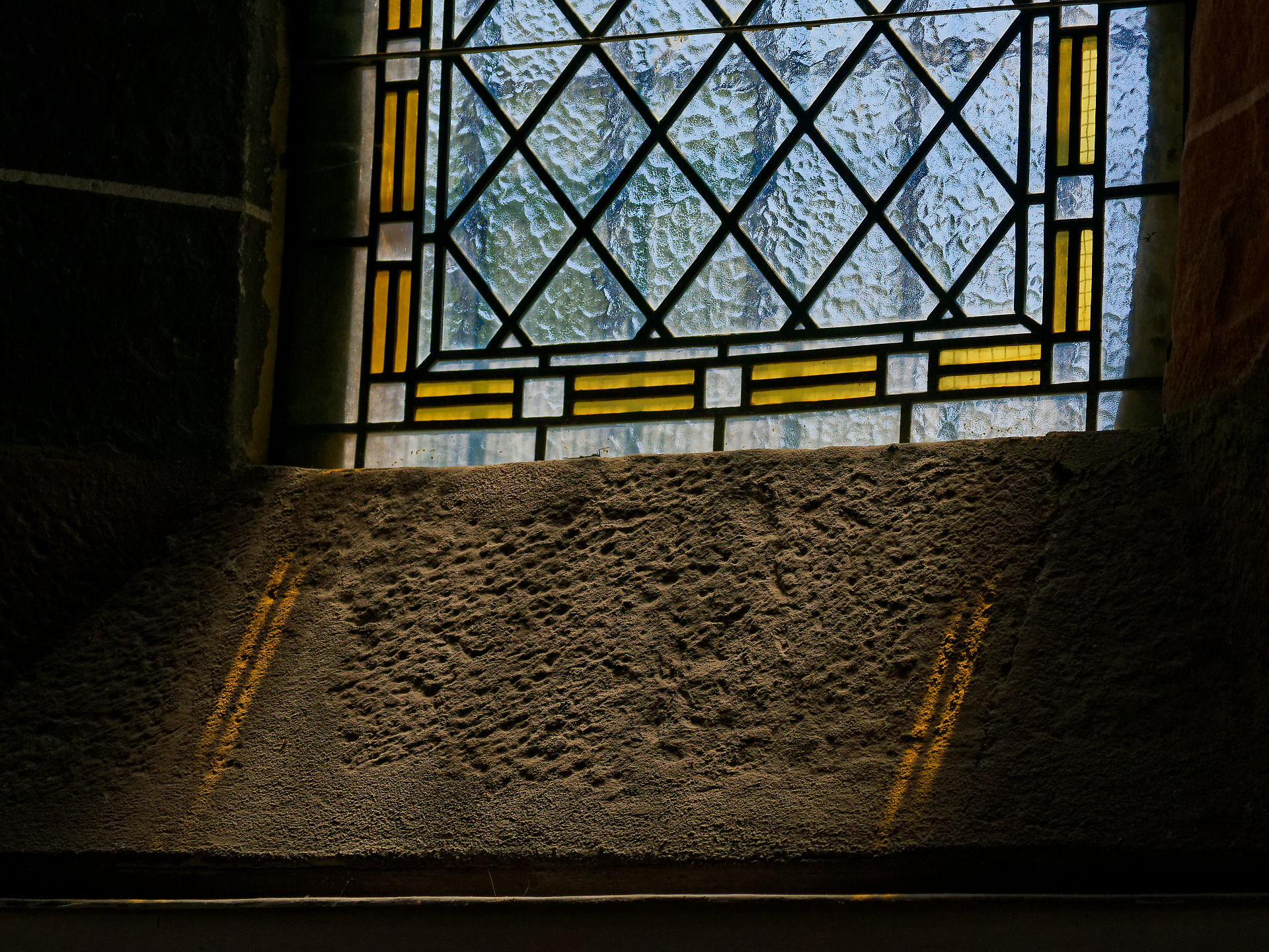Detailaufnahme eines Kirchenfensters in Rumänien mit gelbem Glas und Stein.