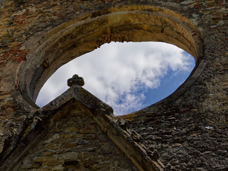 Ruine Kerz, Rumänien: Blick durch ein gotisches Fenster auf den blauen Himmel mit Wolken. Historische Architektur.