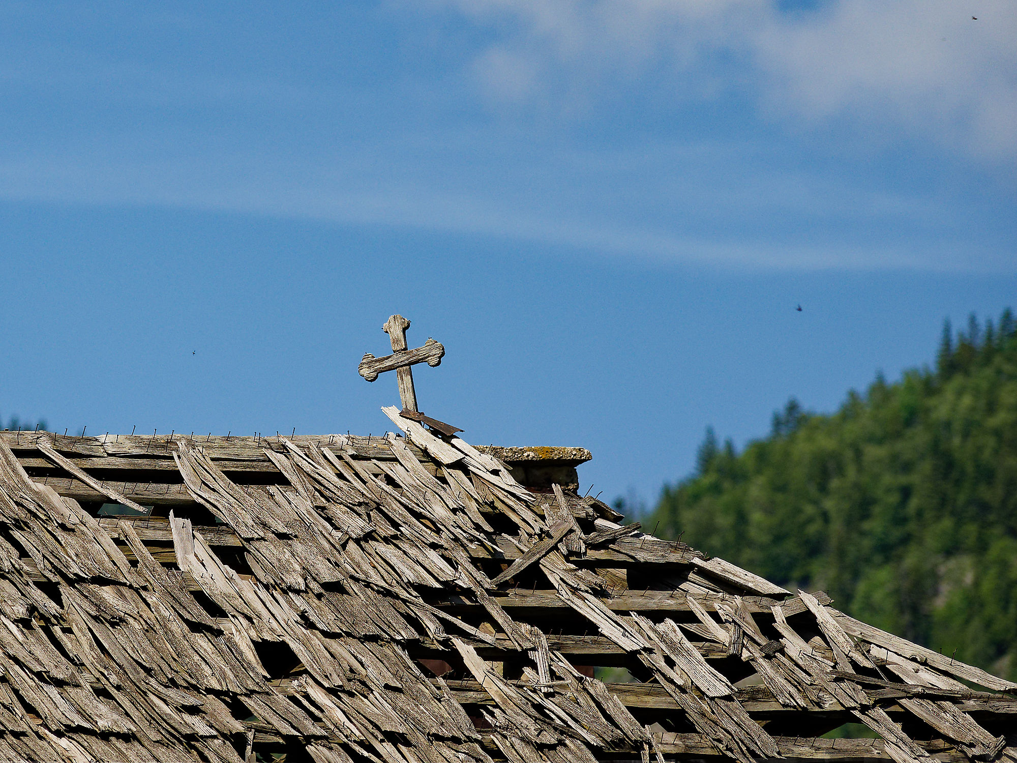 Altes Holzdach mit Kreuz in Rumänien. Piatra Craiului Gebirge im Hintergrund.