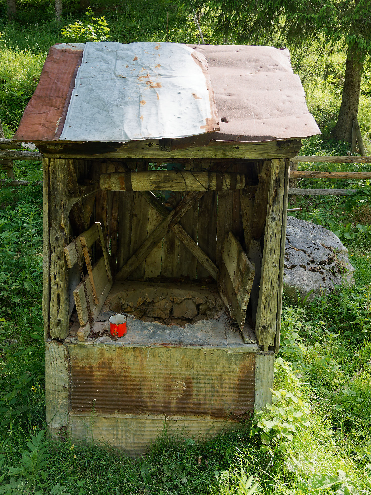Alter Holzbrunnen in Rumänien. Rustikale Landschaft mit roter Tasse. Natur und Tradition.