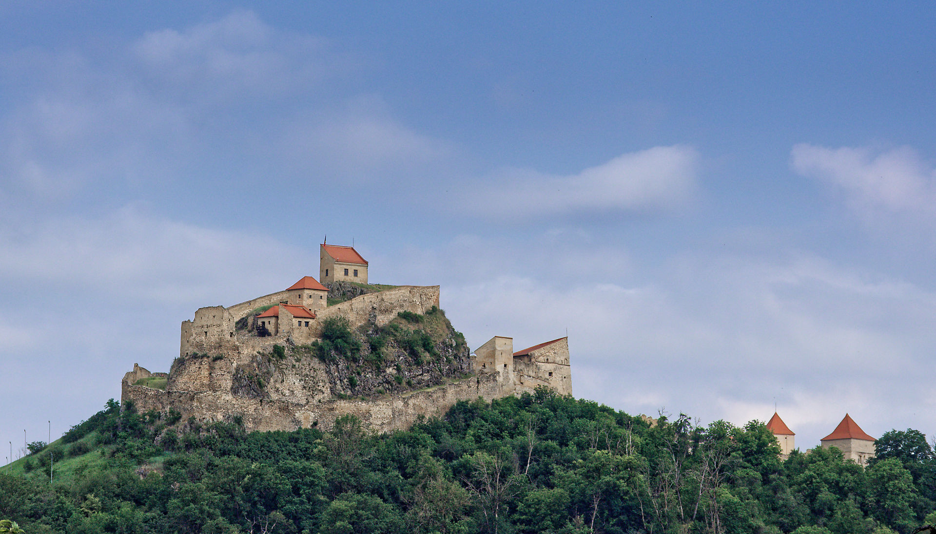 Burg Rupea, Rumänien. Mittelalterliche Festung auf Hügel mit Bäumen und blauem Himmel. Touristische Attraktion.