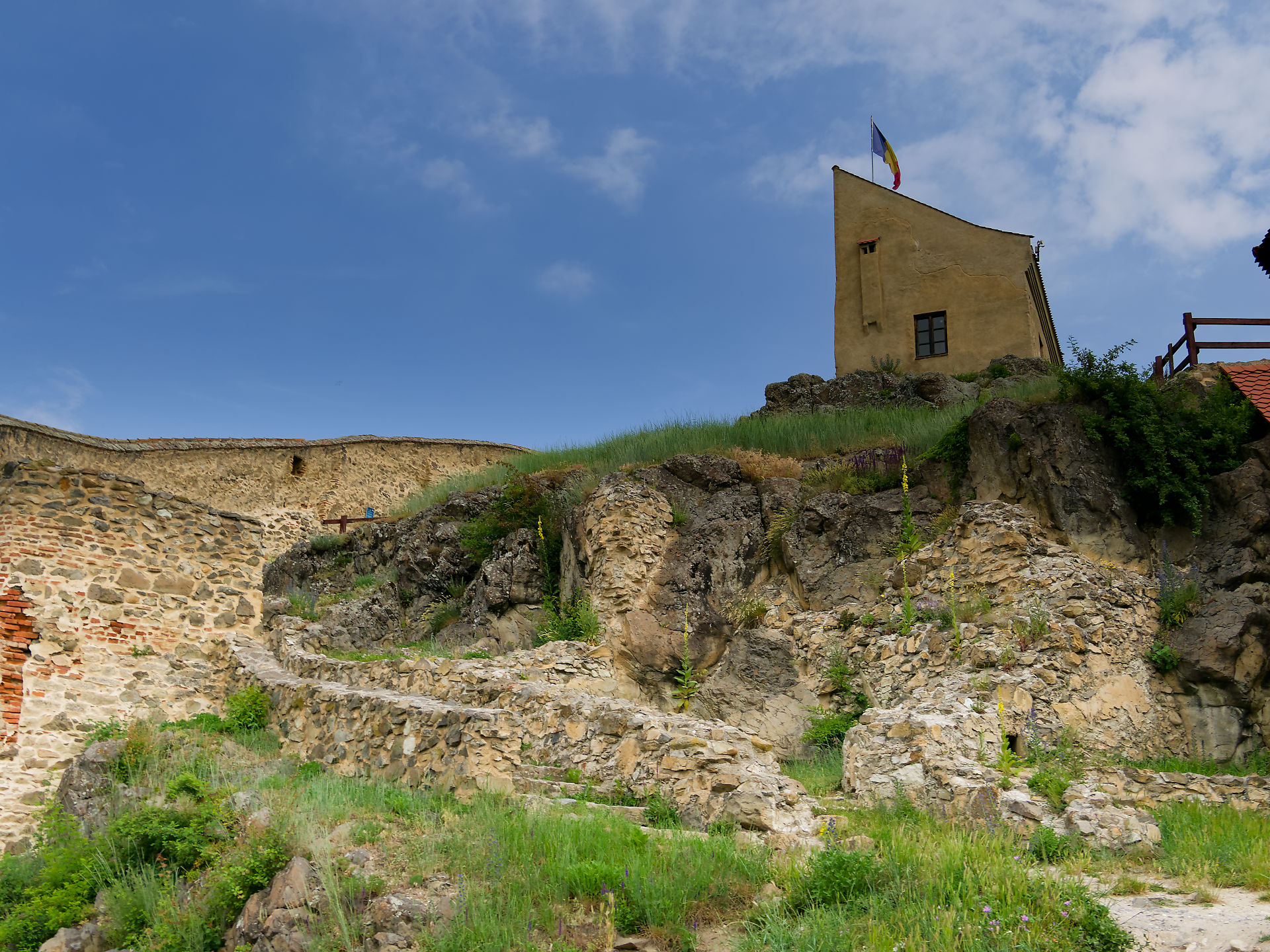 Burg Rupea, Rumänien: Festungsmauer, Turm mit rumänischer Flagge auf einem Hügel. Mittelalterliche Architektur.