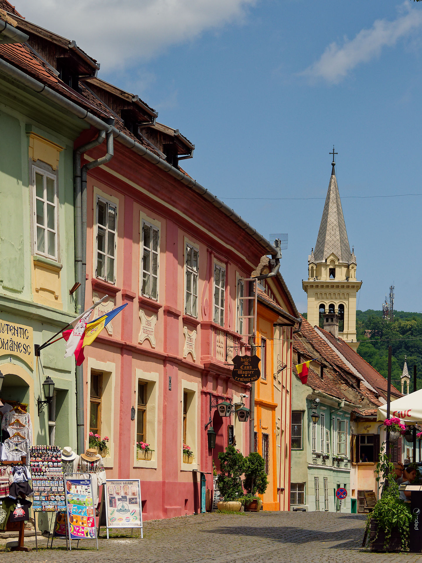 Sighisoara, Rumänien: Bunte Häuserfassaden in einer Gasse der mittelalterlichen Stadt mit Turm im Hintergrund.