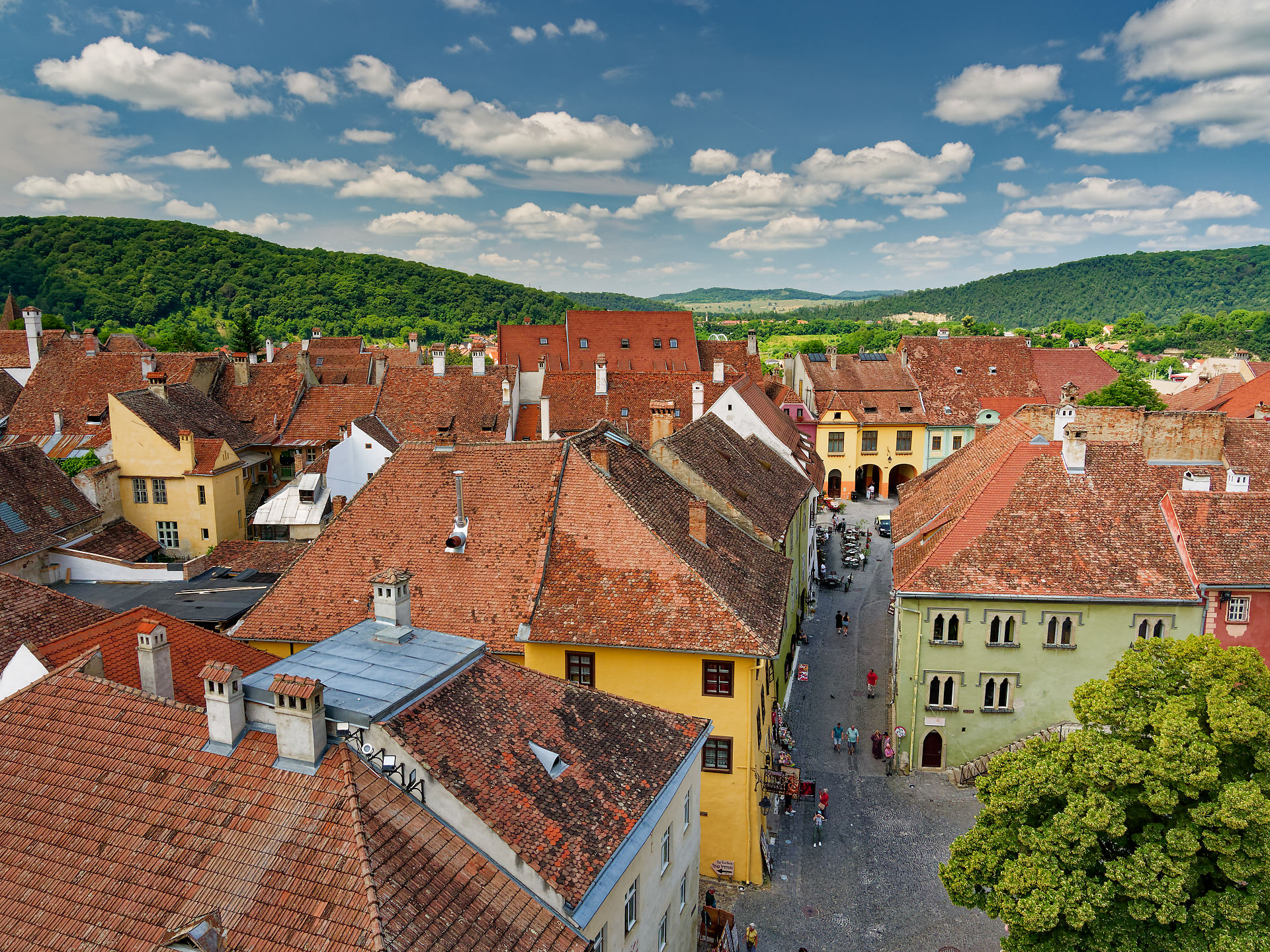 Sighisoara, Rumänien: Blick auf die Altstadt mit roten Dächern und mittelalterlicher Architektur. Hügelige Landschaft im Hintergrund.
