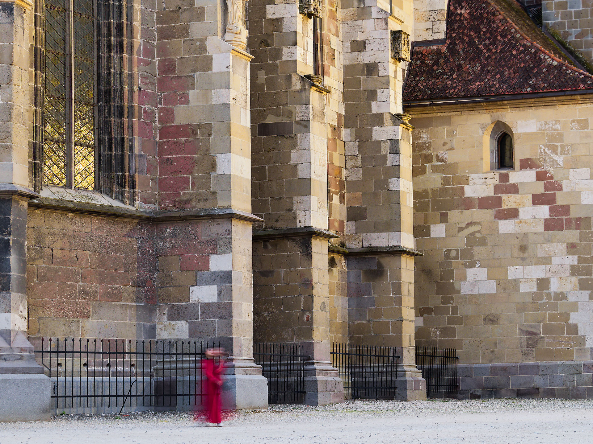 Gotische Architektur: Fassade einer alten Kirche mit Fenster und Person in Rot. Historisches Gebäude. Long exposure