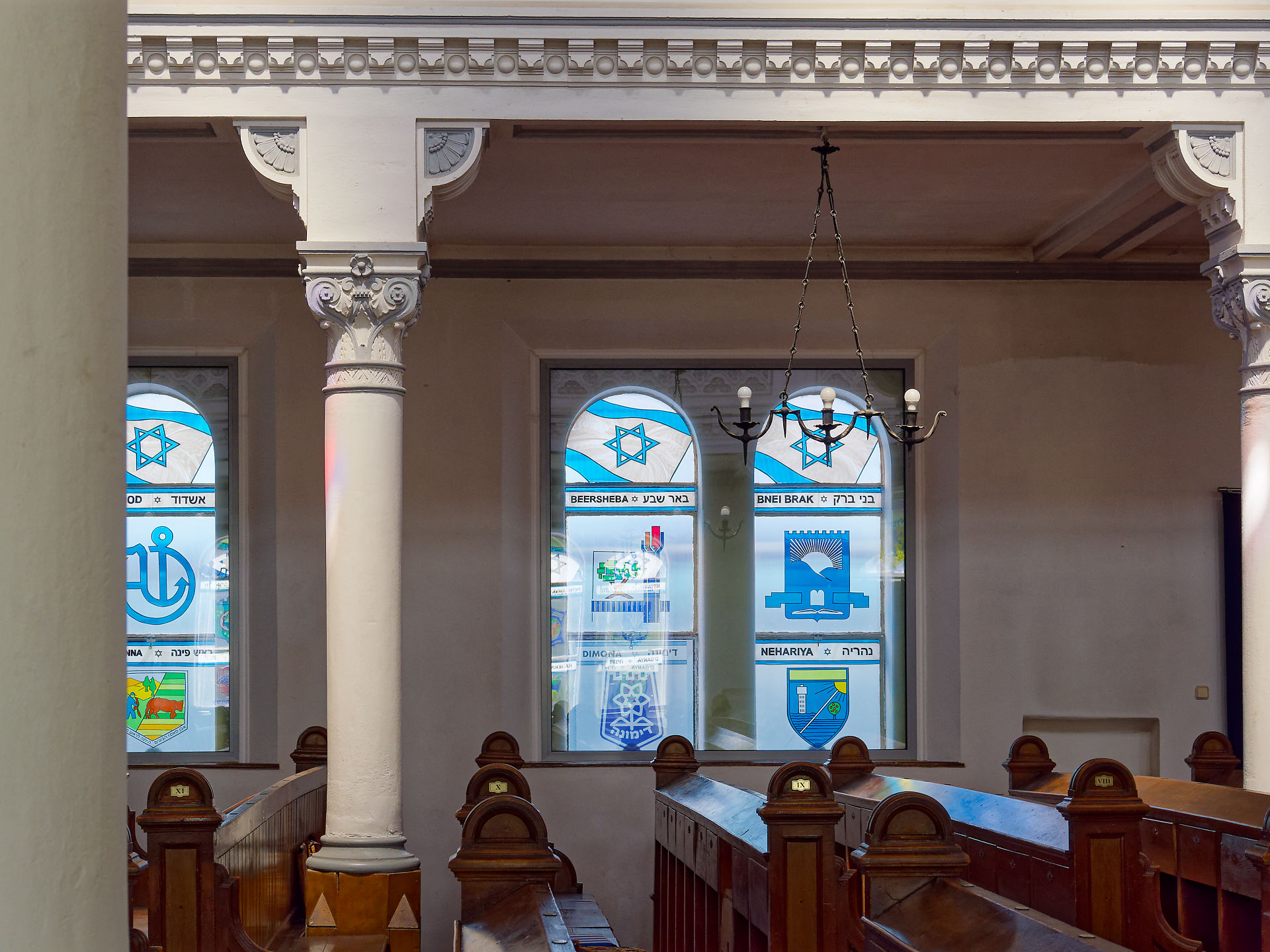 Innenraum der Synagoge mit Buntglasfenstern, Säulen und Holzbänken. Jüdische Architektur.