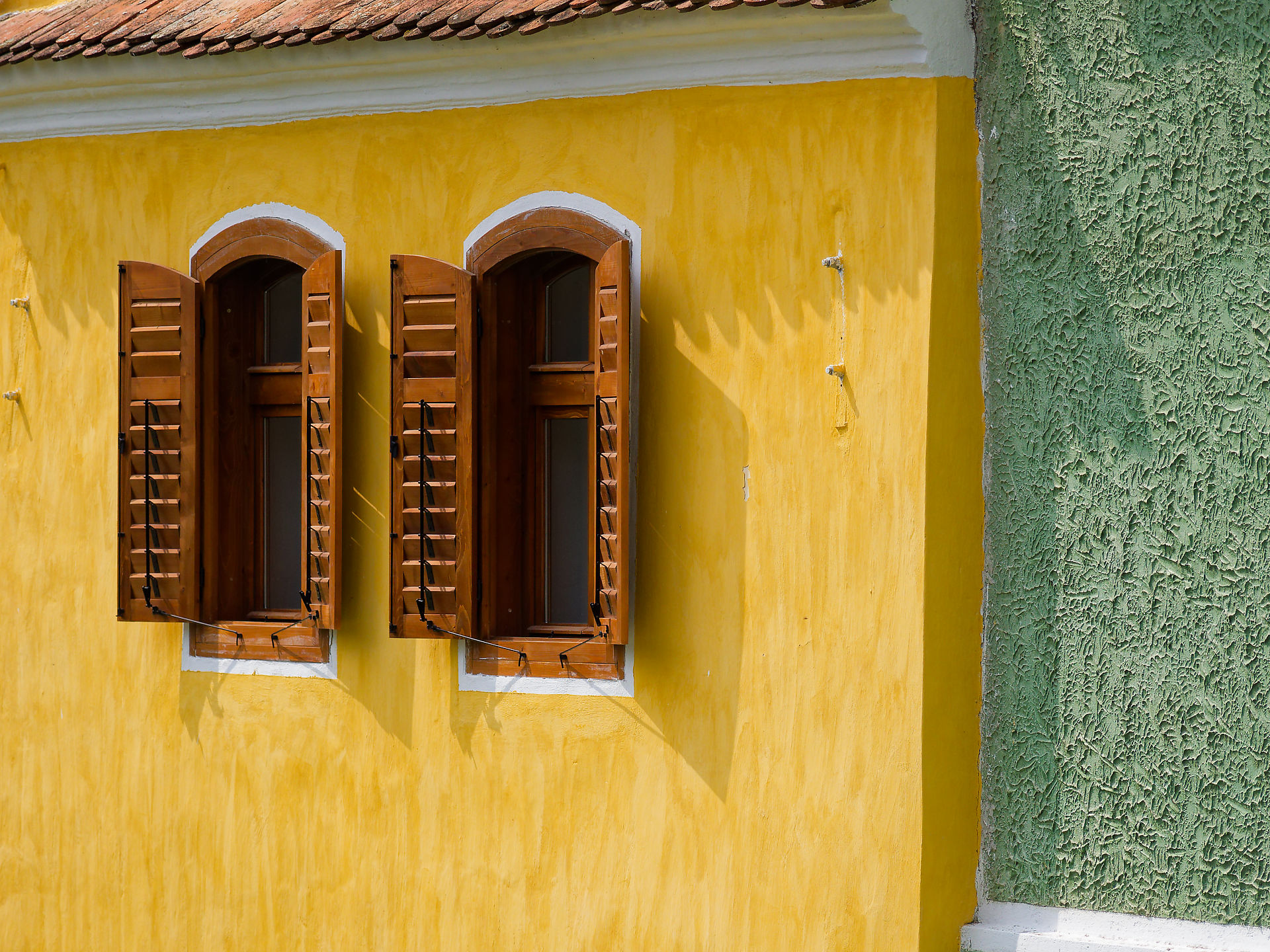 Gelbe Fassade in Viscri, Rumänien. Holzfensterläden und grüne Wand. Architektur in Siebenbürgen.