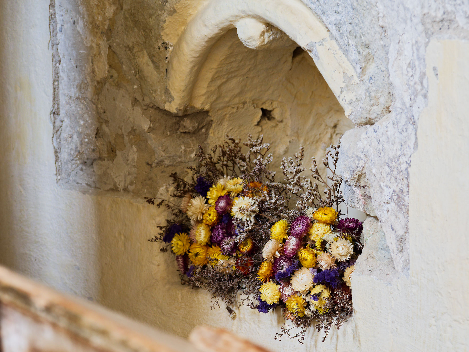 Blumen in einer Nische, Viscri, Rumänien. Mittelalterliche Architektur, gelbe und lila Blumenarrangements.