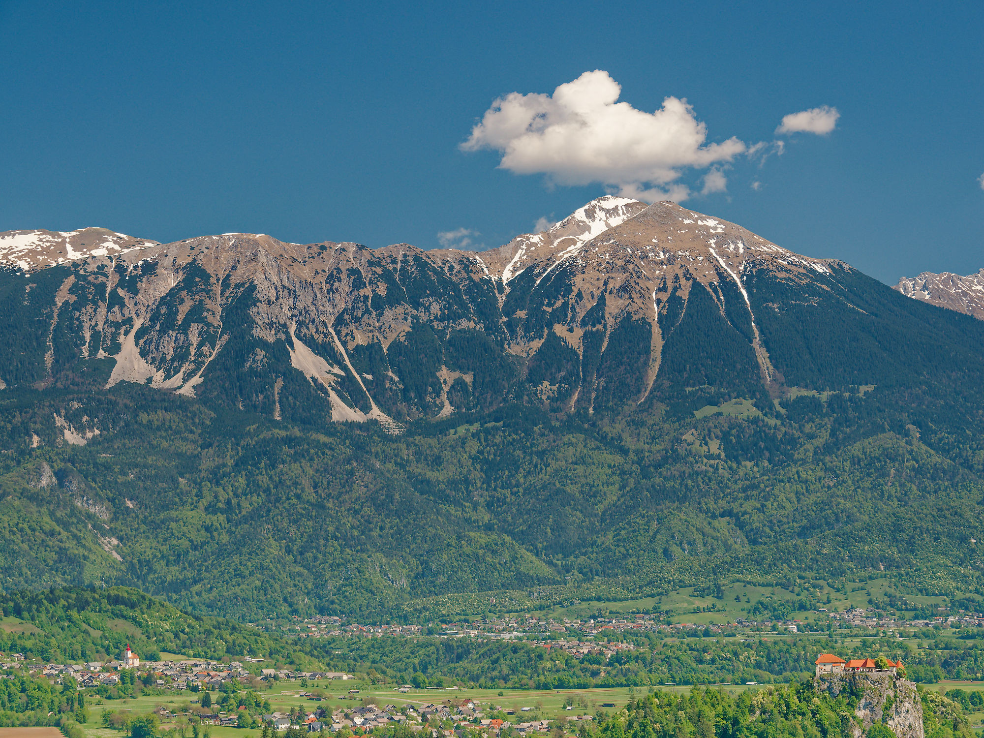 Bled, Slowenien: Berglandschaft mit Burg und grünen Wäldern unter blauem Himmel. Reiseziel.