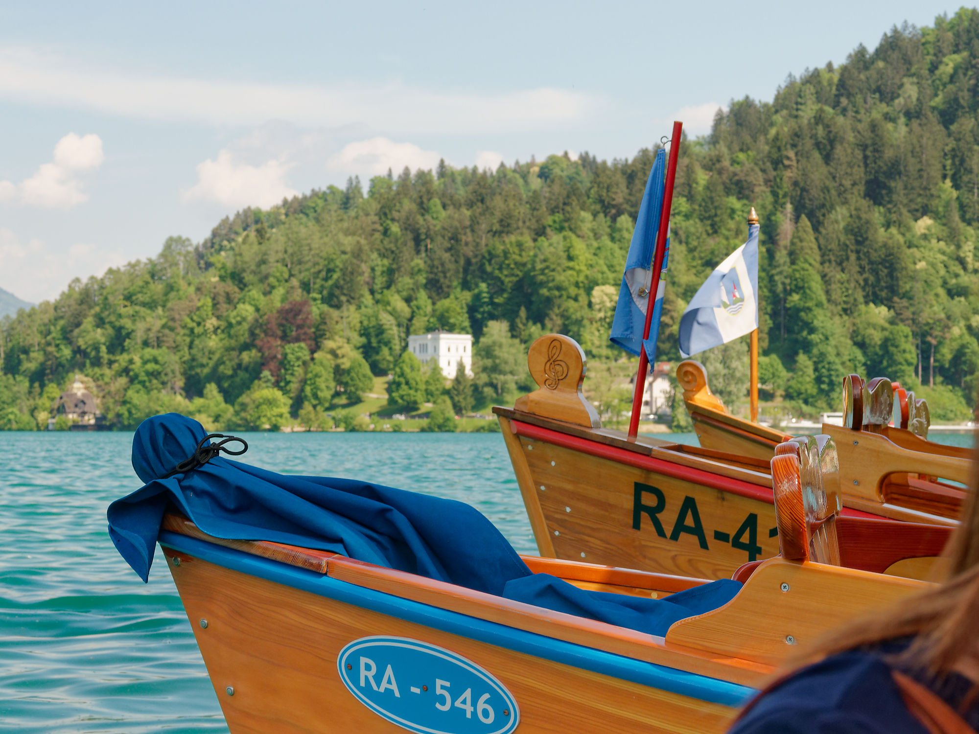 Bleder See, Slowenien: Traditionelle Holzboote auf dem klaren Wasser vor grünen Hügeln. Urlaubsparadies.