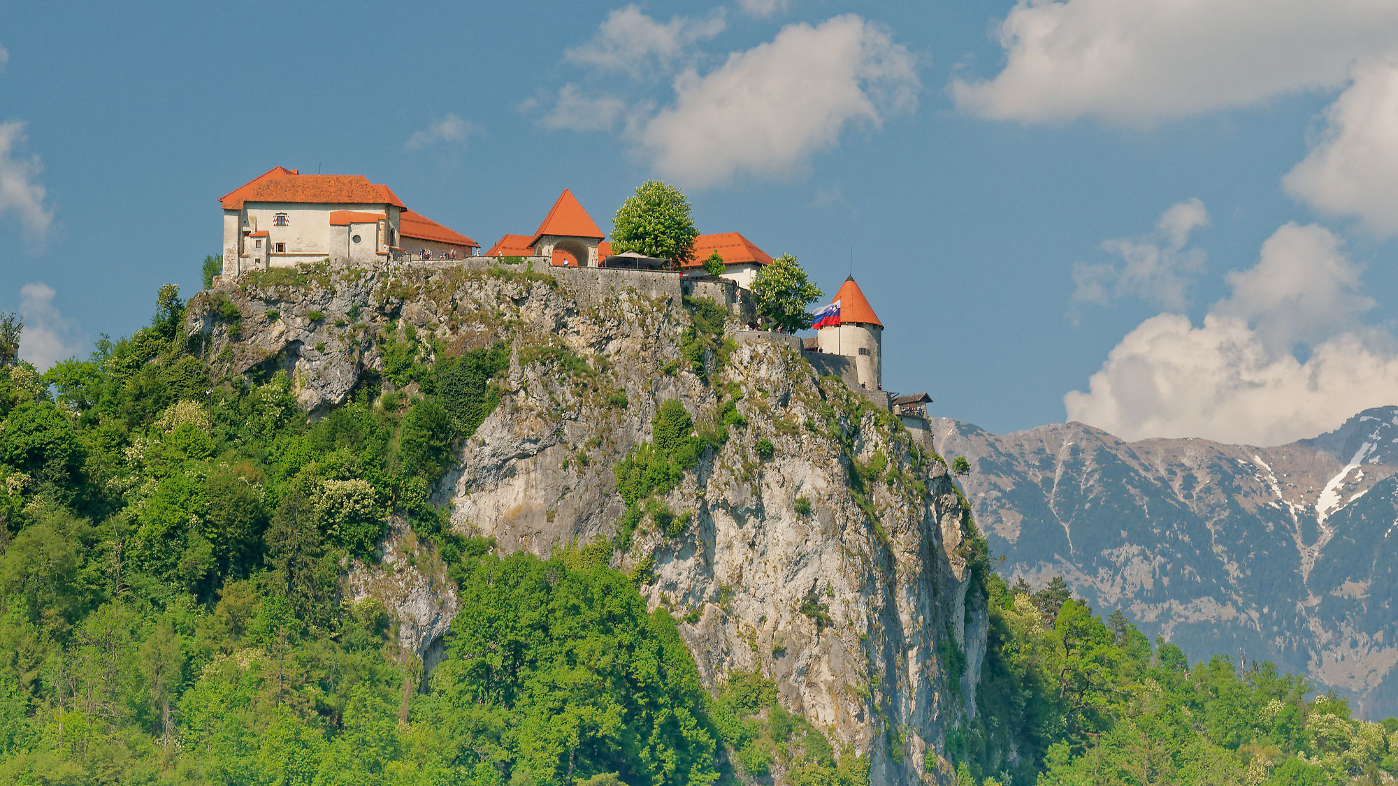 Bled, Slowenien: Berglandschaft mit Burg und grünen Wäldern unter blauem Himmel. Reiseziel.