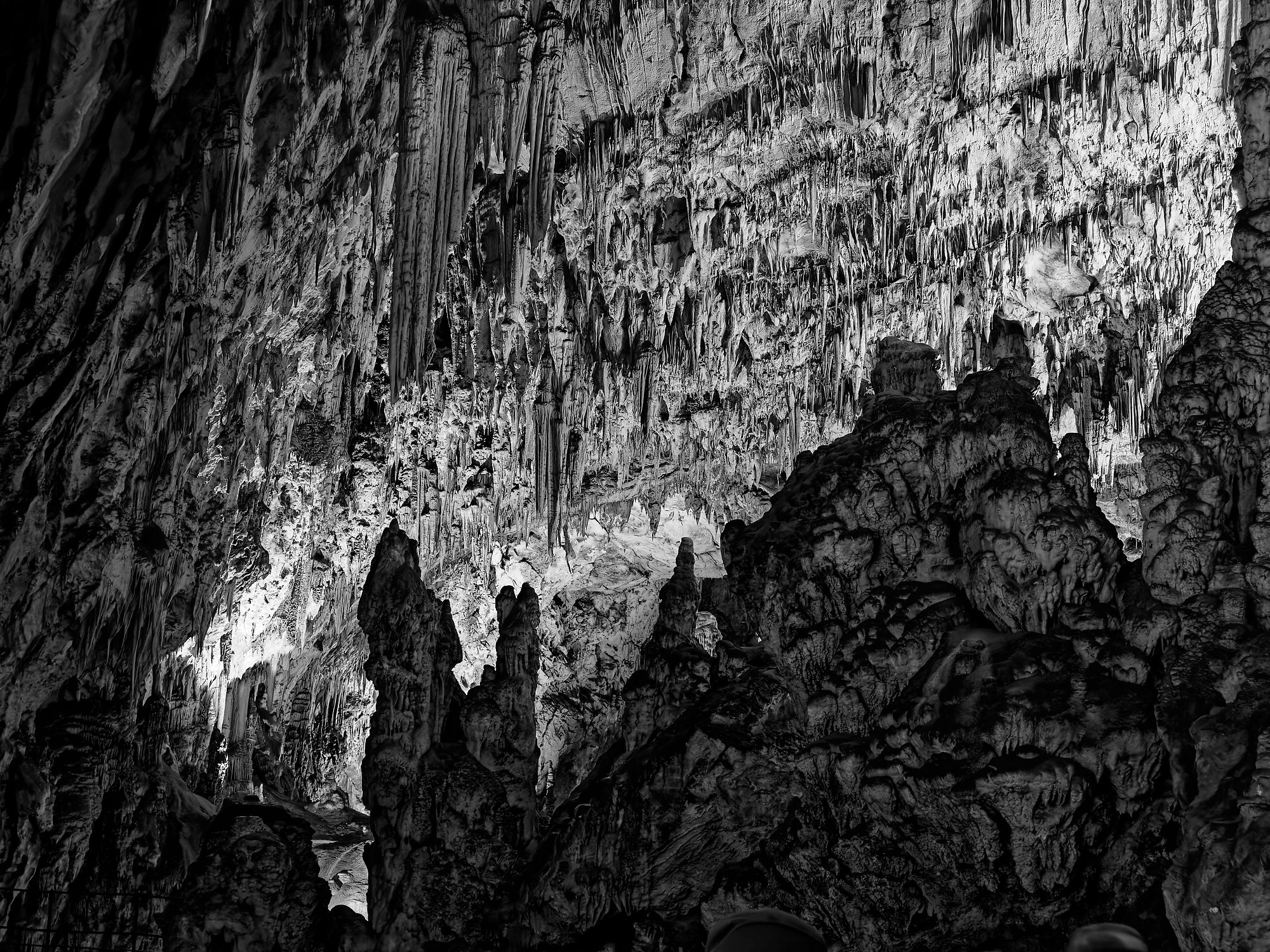 Schwarzweißfoto der Höhle von Postojna, Slowenien, mit Stalaktiten und Stalagmiten.