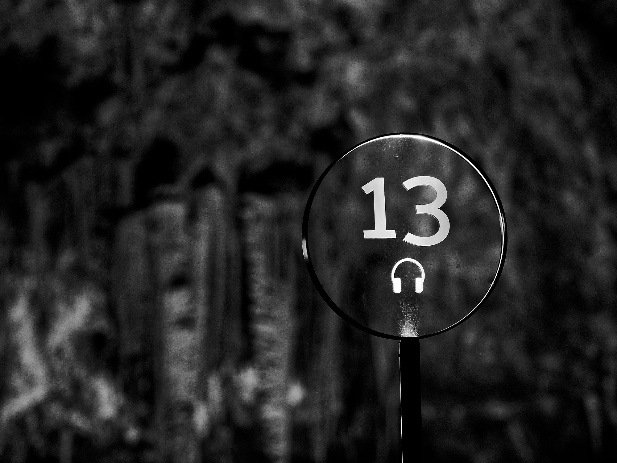 Schild Nummer 13 in der Höhle von Postojna, Slowenien. Kopfhörer-Symbol. Schwarz-Weiß-Fotografie.