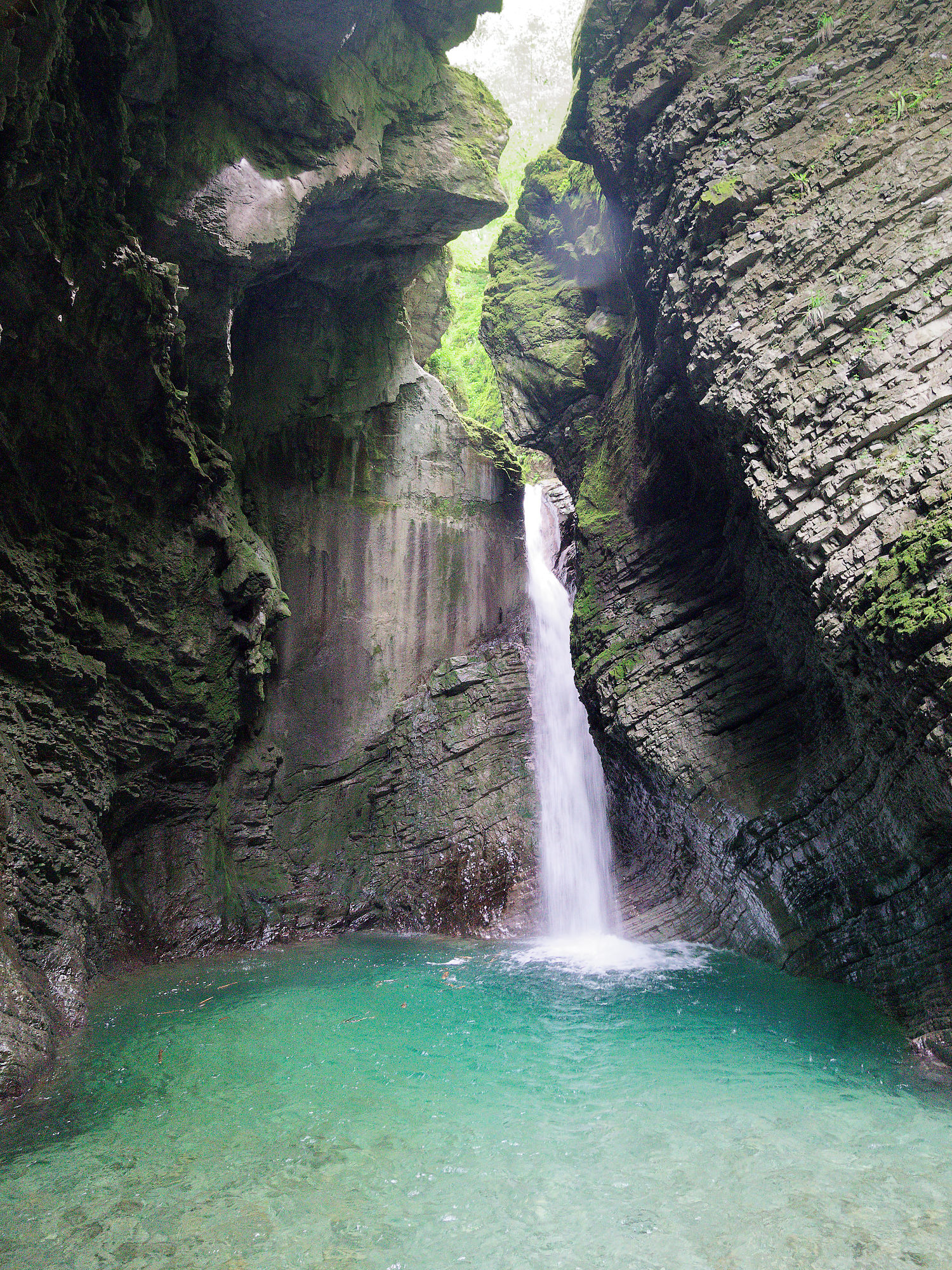 Soca, Slowenien: Smaragdgrüner Pool unter einem Wasserfall in einer felsigen Schlucht. Natur pur.
