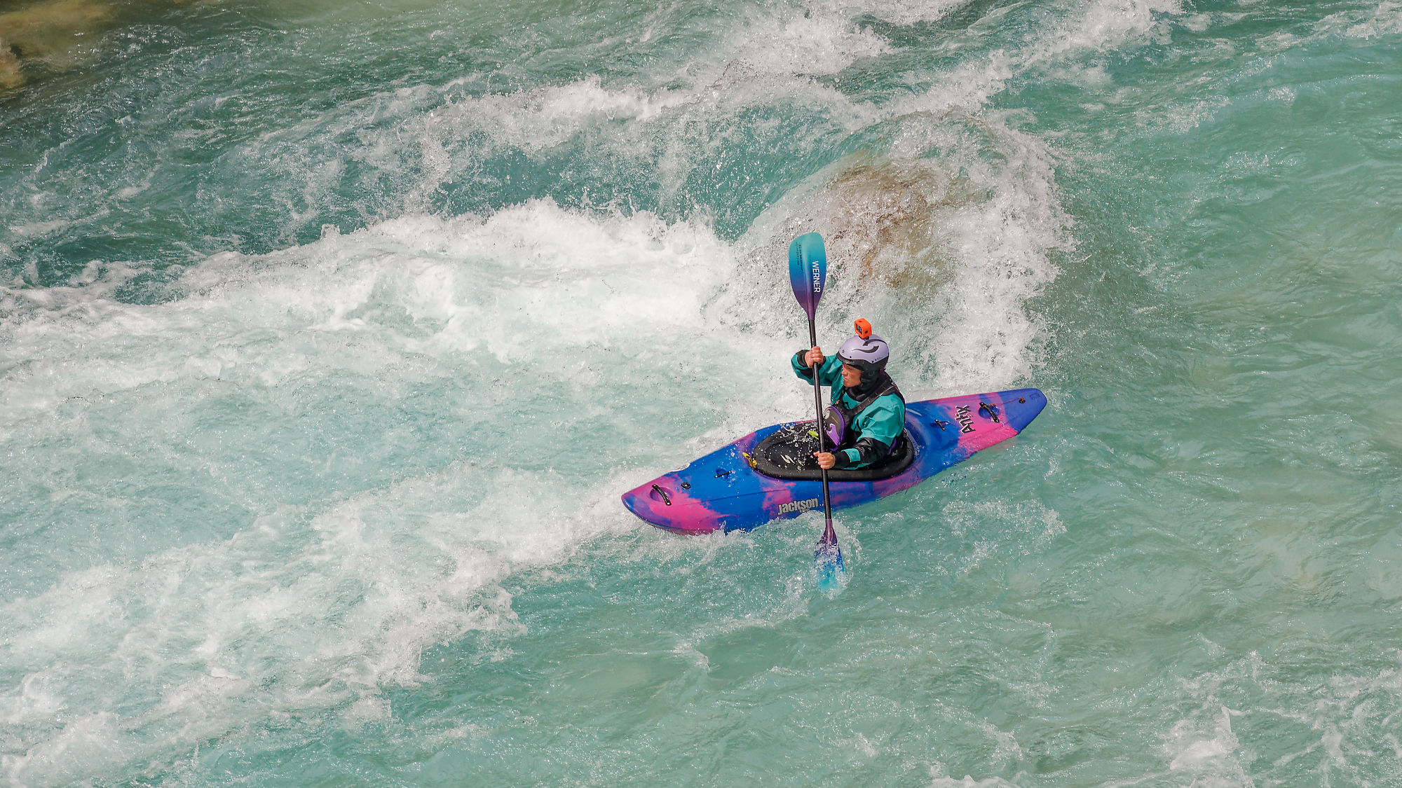 Abenteuerliches Kajakfahren auf dem türkisblauen Fluss Soča in Slowenien, umgeben von grüner Natur und steinigen Ufern – Outdoor-Sport und Naturlandschaft.