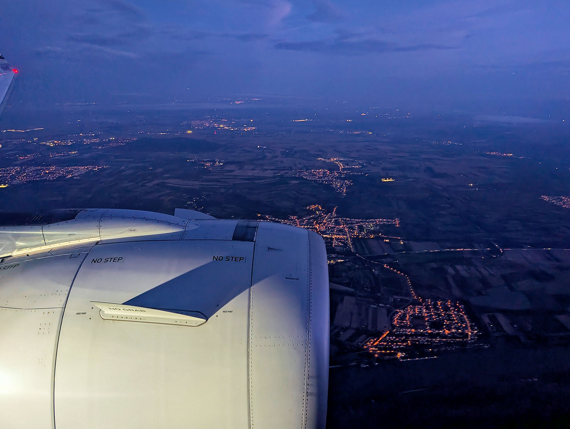 Flugzeug im Landeanflug auf Frankfurt (FRA) bei Nacht. Blick aus dem Fenster auf Triebwerk und Lichter.