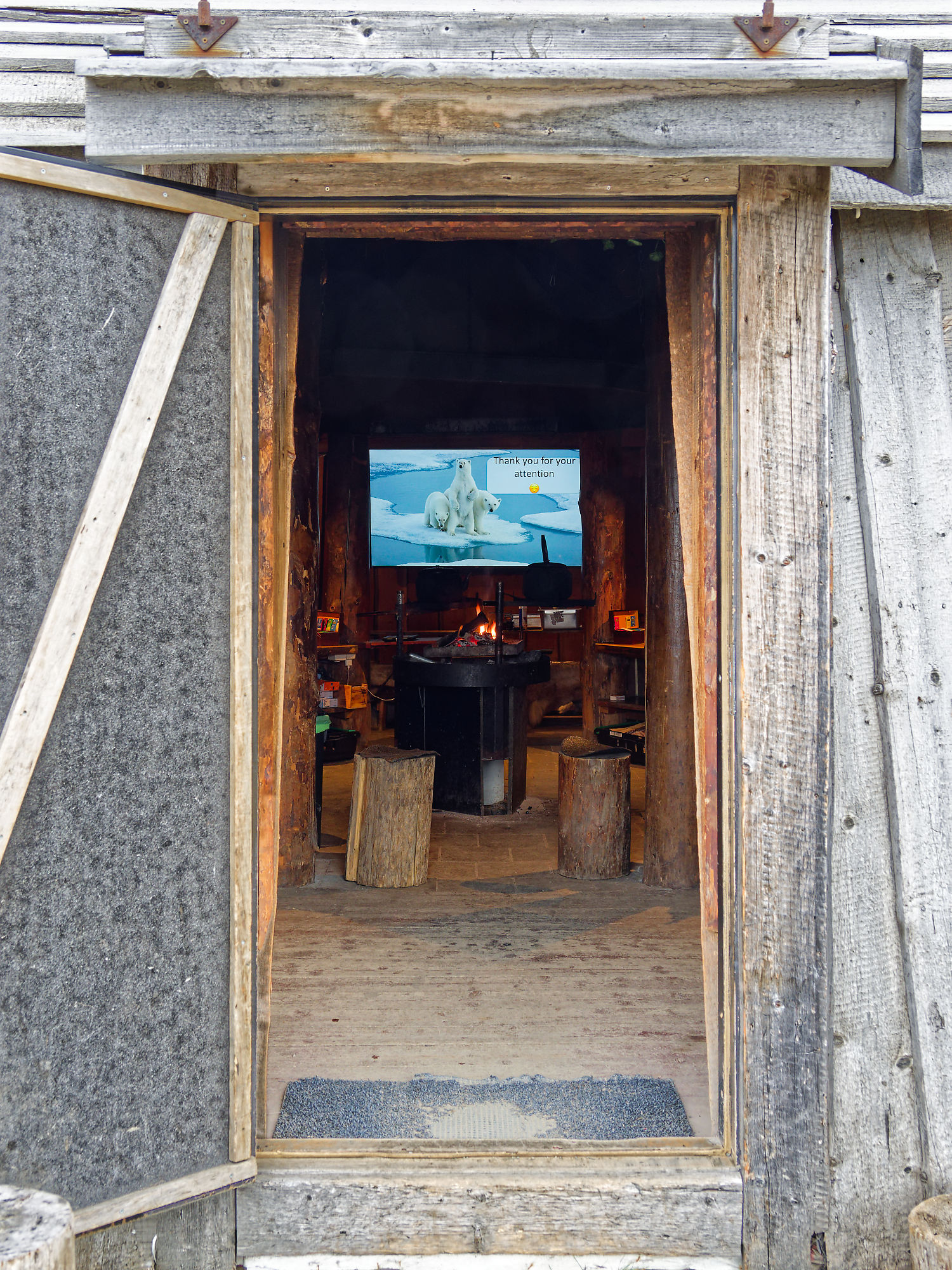 Camp Barentz Hütte: Blick in rustikalen Innenraum mit Bären-Präsentation auf Leinwand. Gemütliche Atmosphäre.