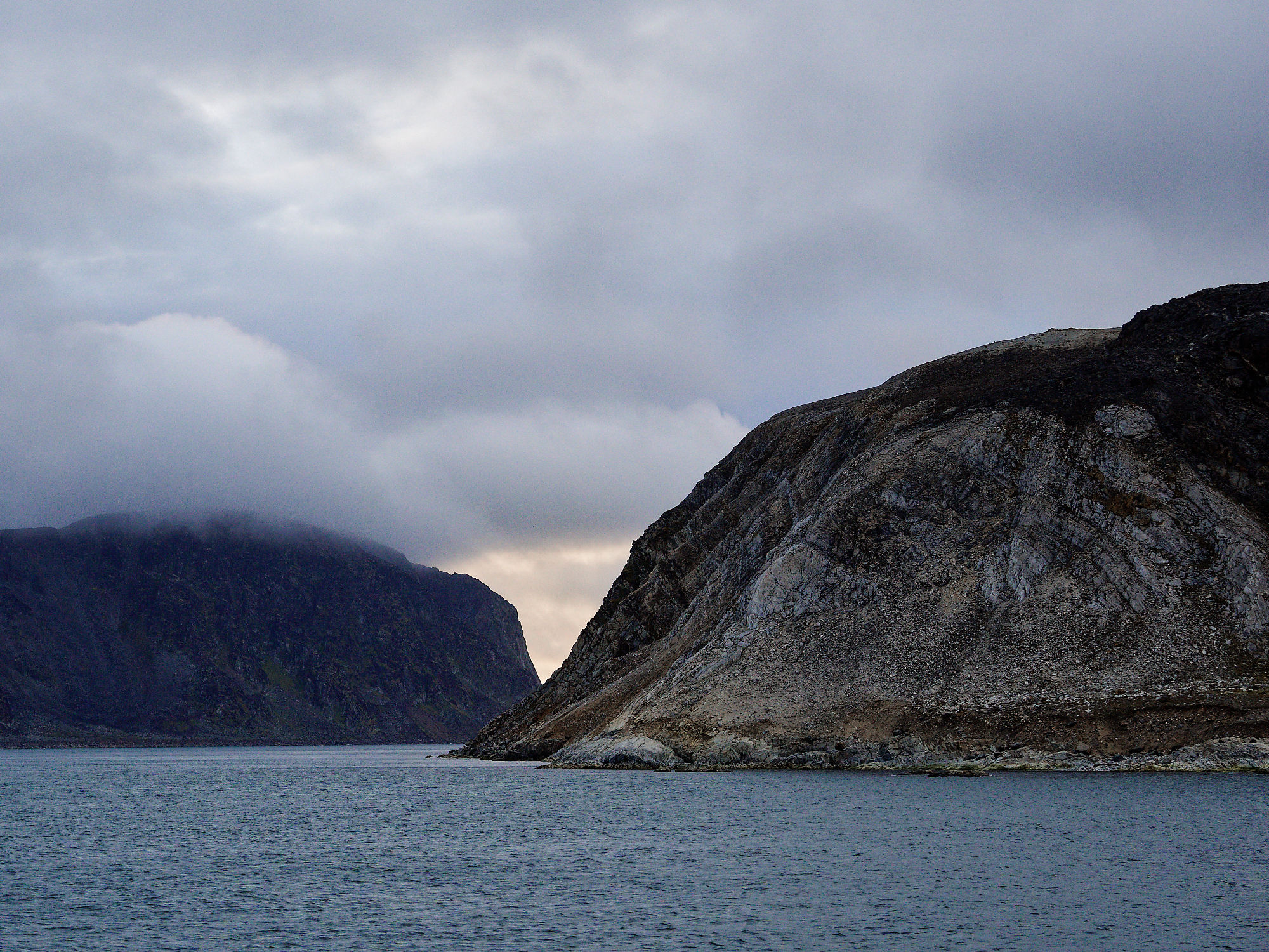 Fuglefjorden, Spitzbergen. Landschaft mit Bergen, Wasser und bewölktem Himmel. Naturreise.