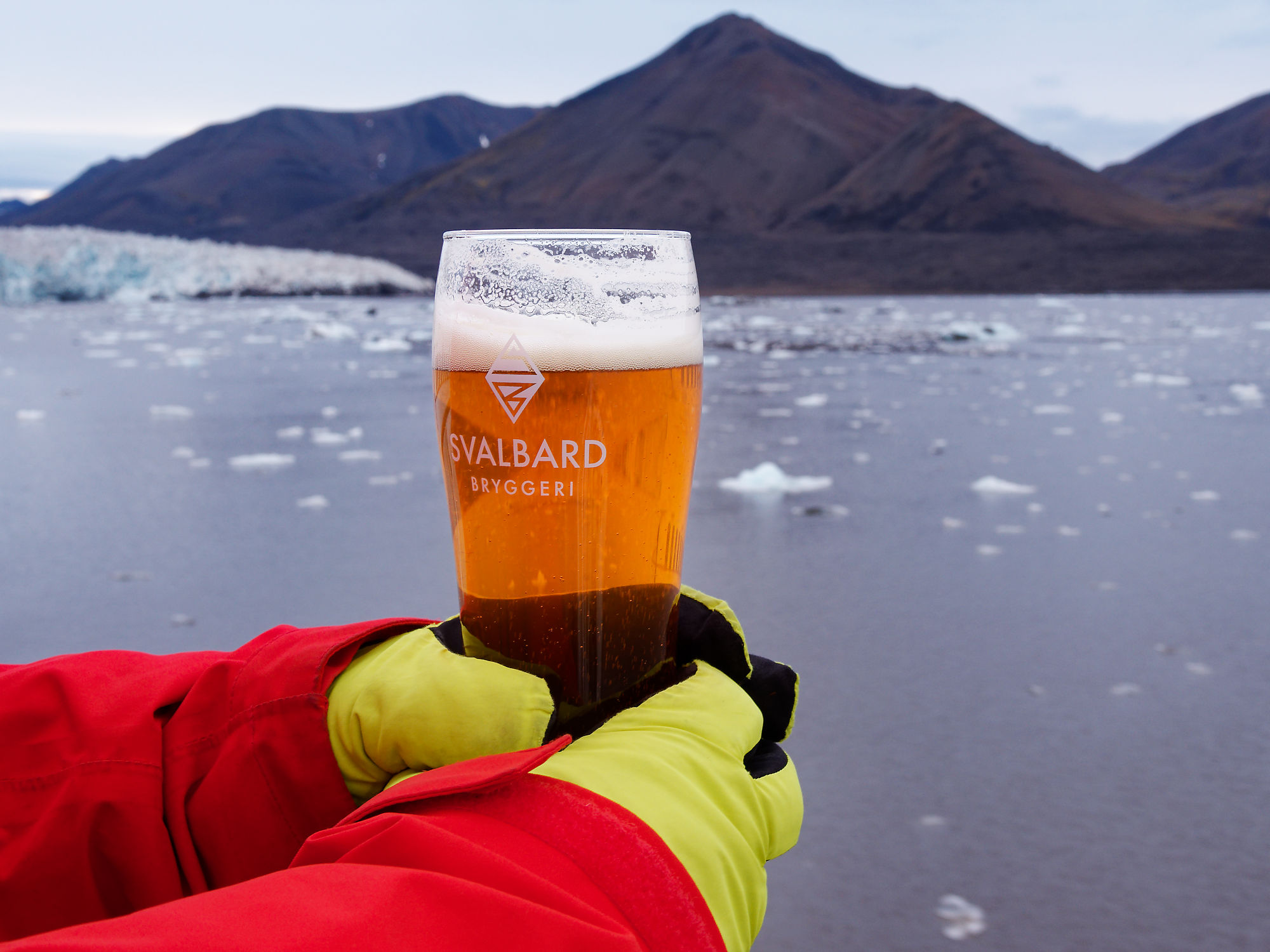 Svalbard Bier vor arktischer Landschaft. Gebirge und Eis im Hintergrund. Kaltes, erfrischendes Getränk.