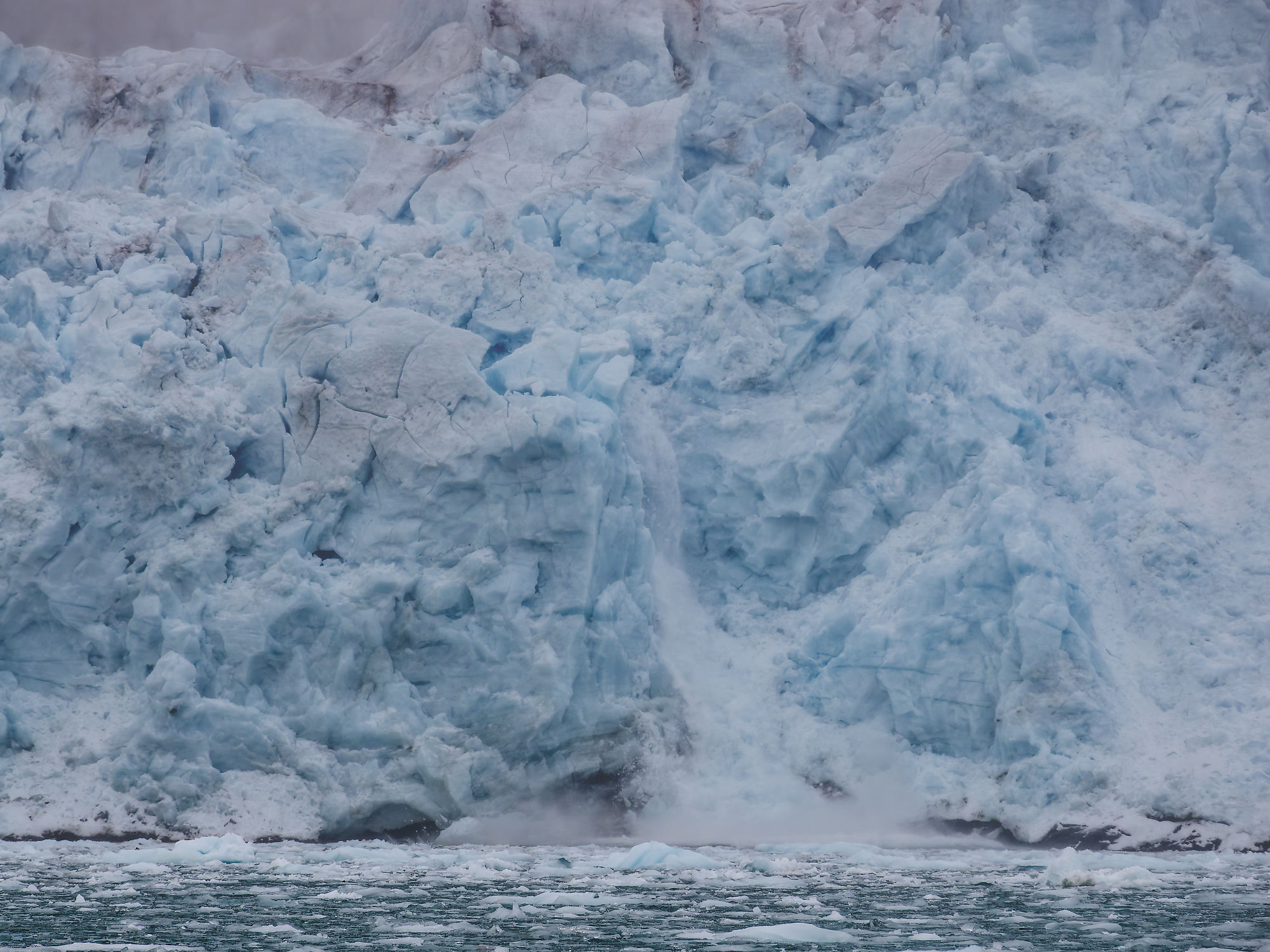 Eisbergkalben in Liefdefjorden, Spitzbergen. Gletscherabbruch mit Wasserfall ins Meer. Arktis-Kreuzfahrt.